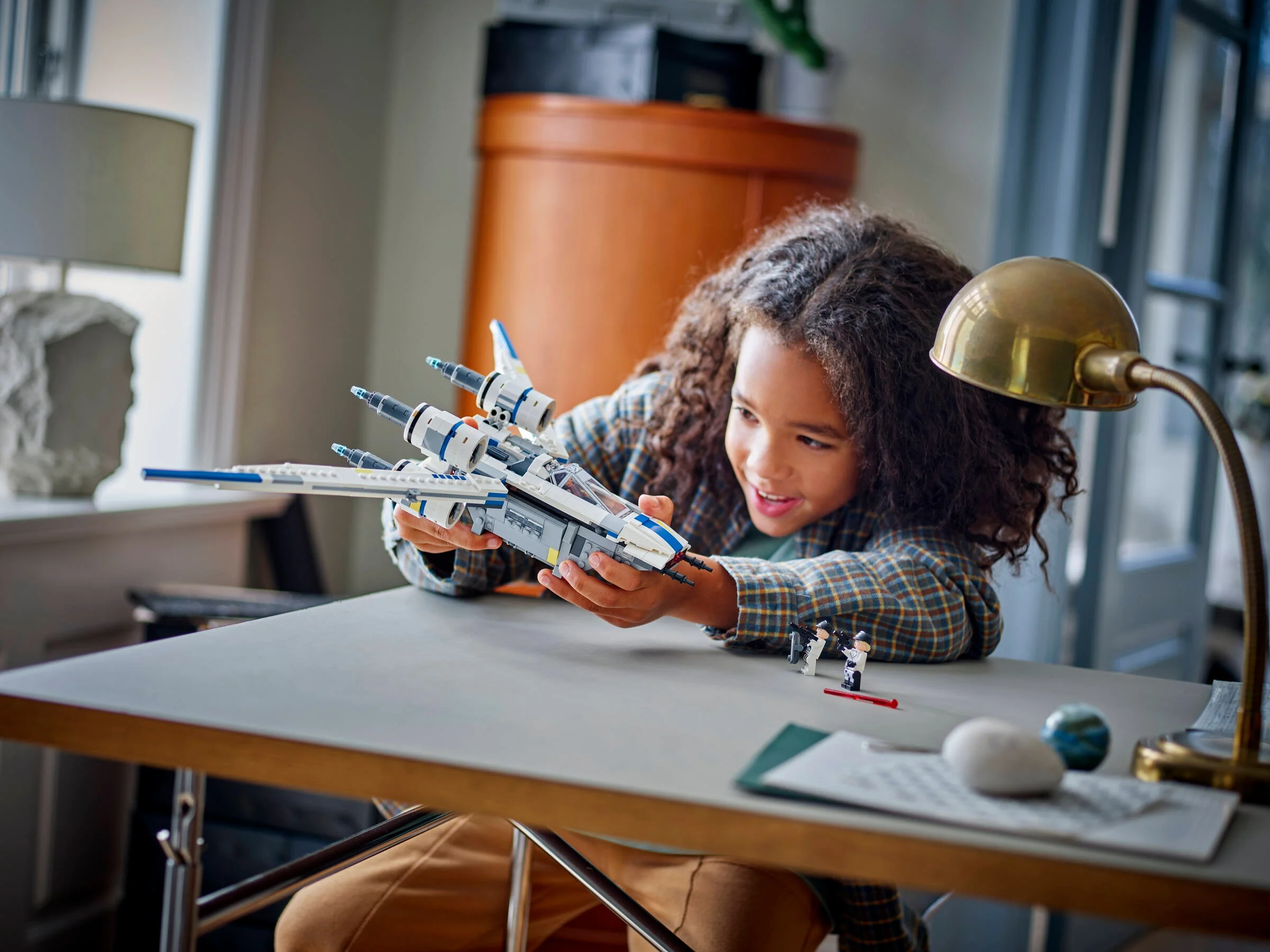 Copil se joacă cu modelul U-wing Starfighter, arătând entuziasm și creativitate.