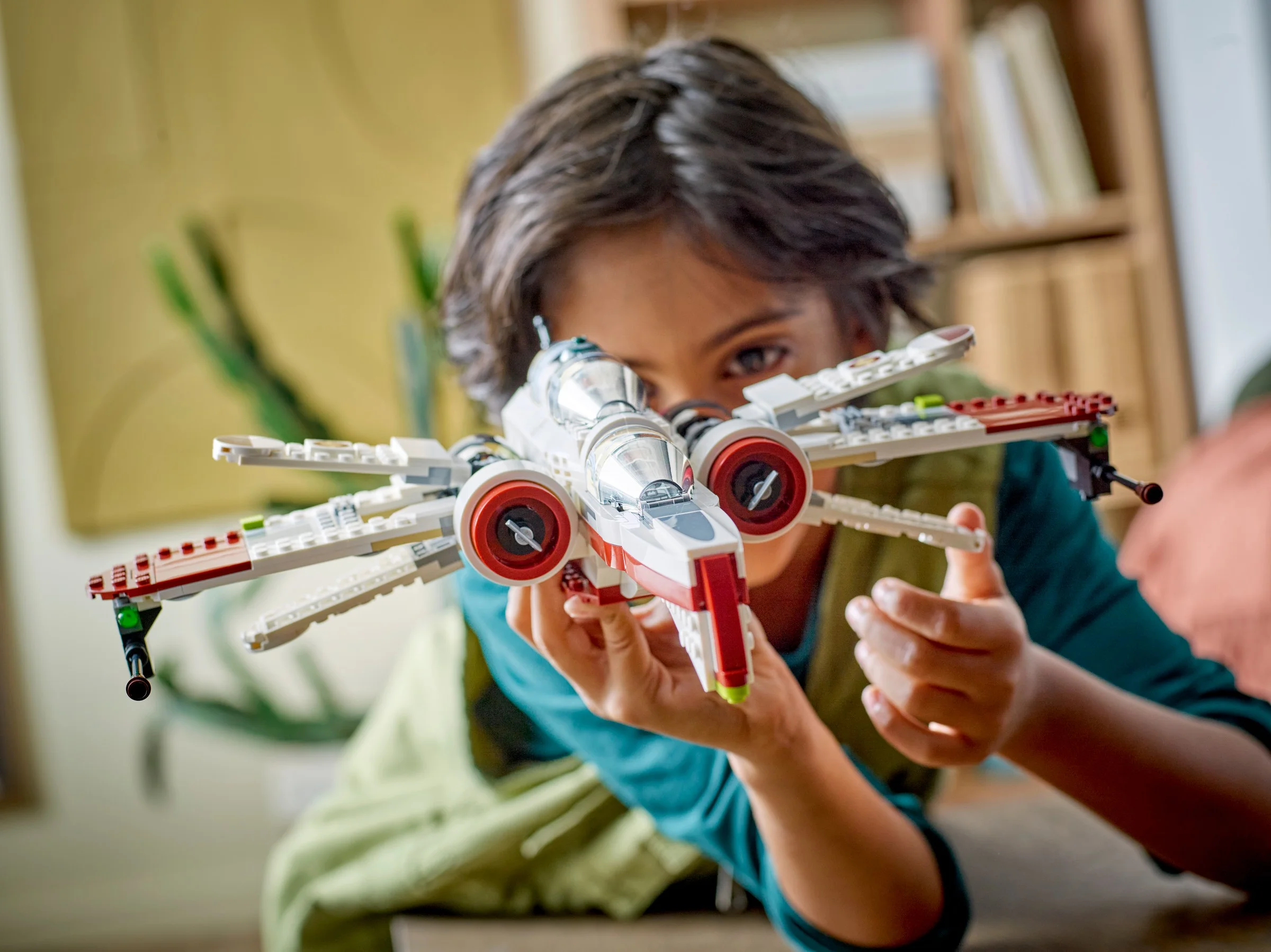 Copil ține în mână ARC-170 Starfighter LEGO, părând că zboară. Modelul este detaliat, alb și roșu.