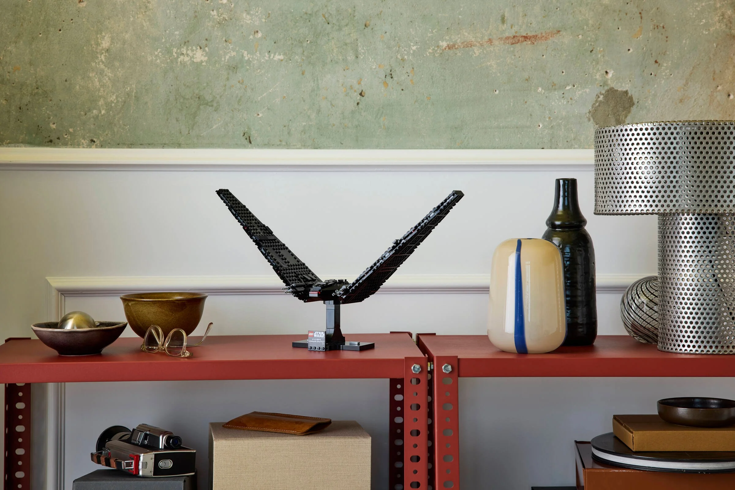 Naveta lui Kylo Ren expusă pe un raft roșu, într-un decor modern. Aspect elegant și minimalist.