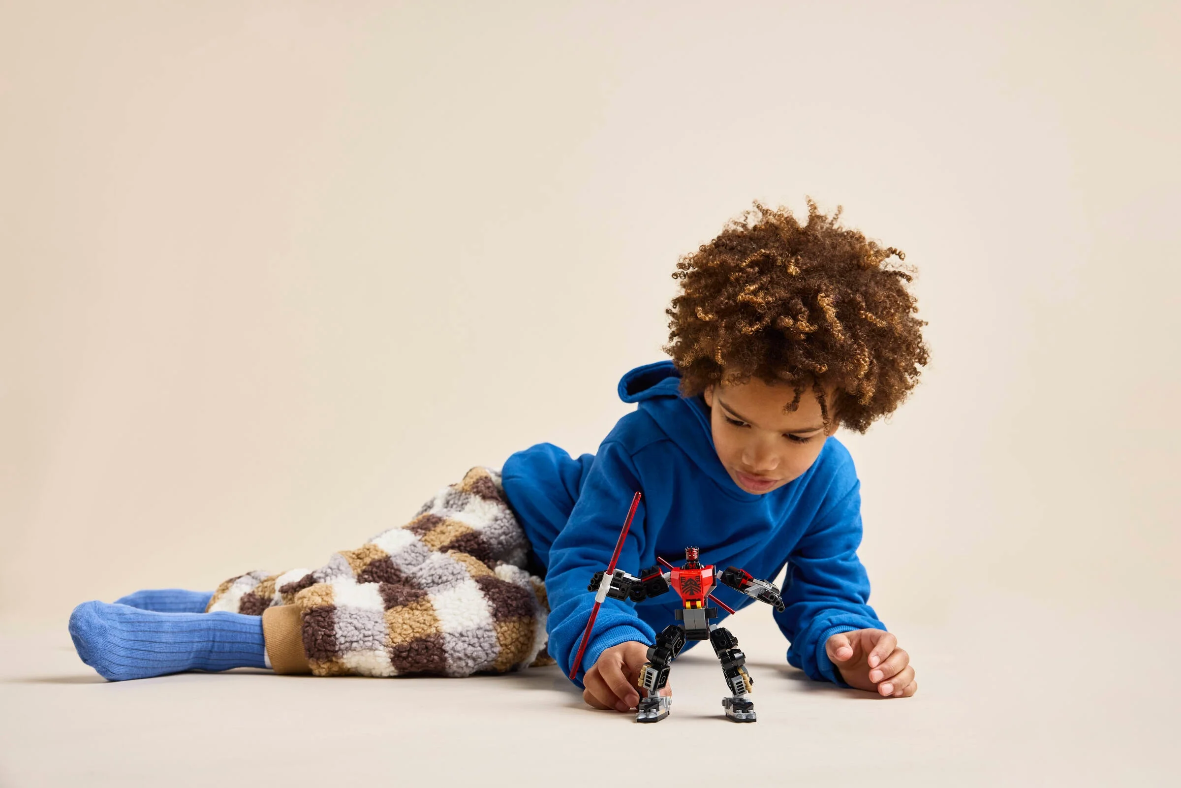 Copil se joacă cu un mech Darth Maul LEGO. Imagine prietenoasă și atrăgătoare.