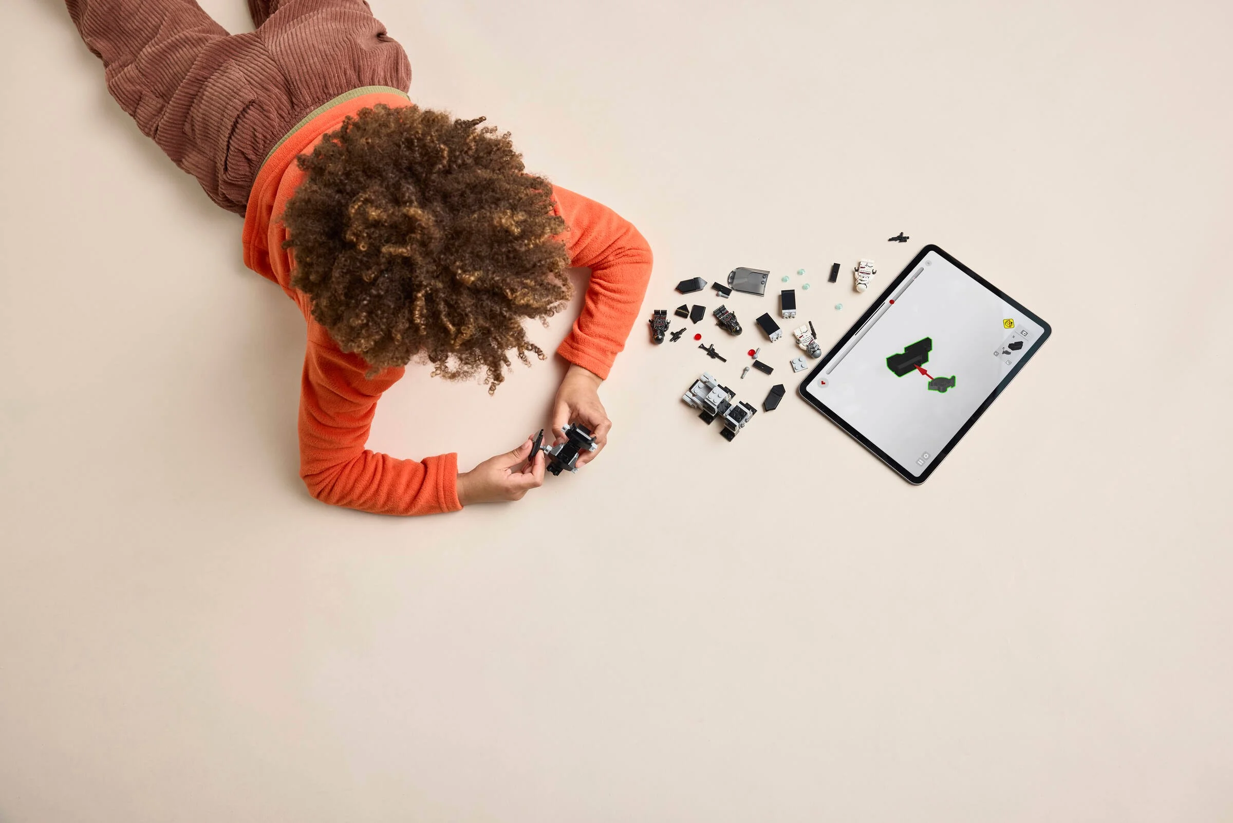 Un copil construiește un set LEGO, folosind instrucțiuni digitale pe tabletă.