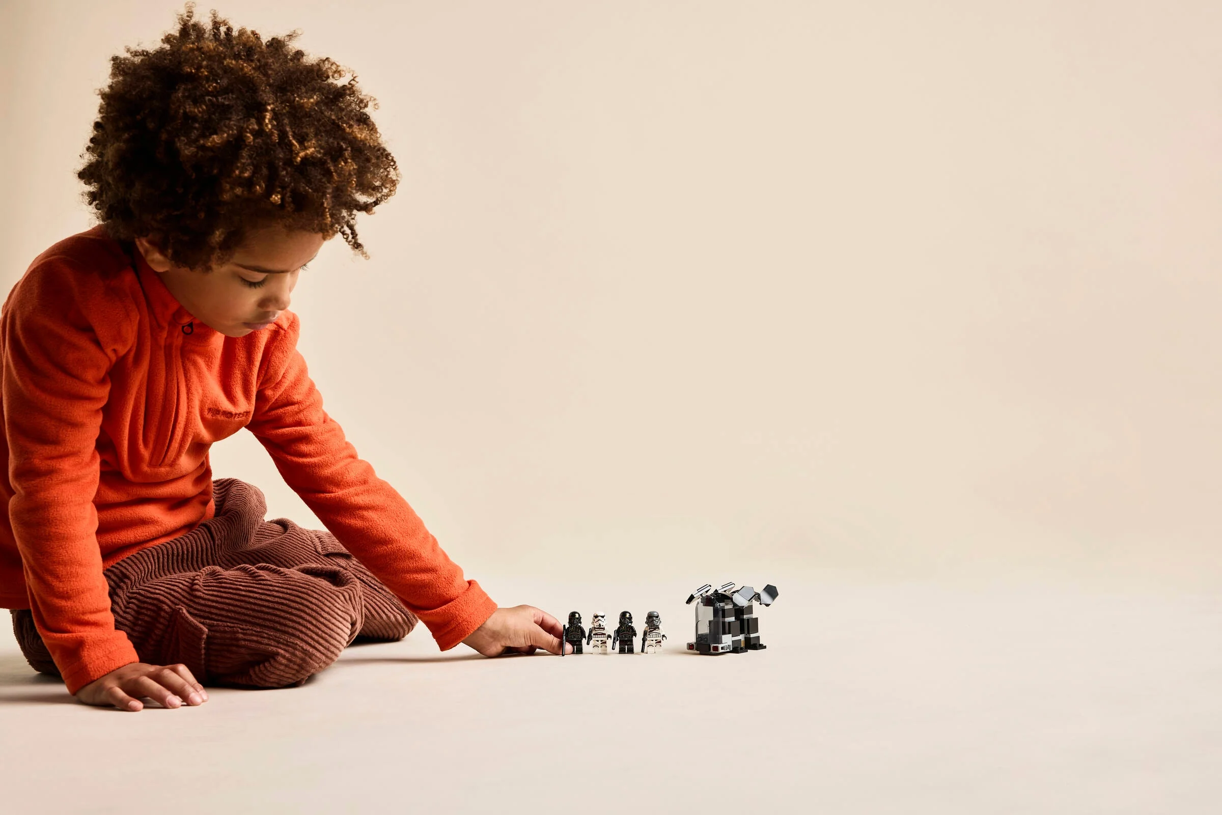 Copil se joacă cu minifigurinele și construcția LEGO Star Wars.