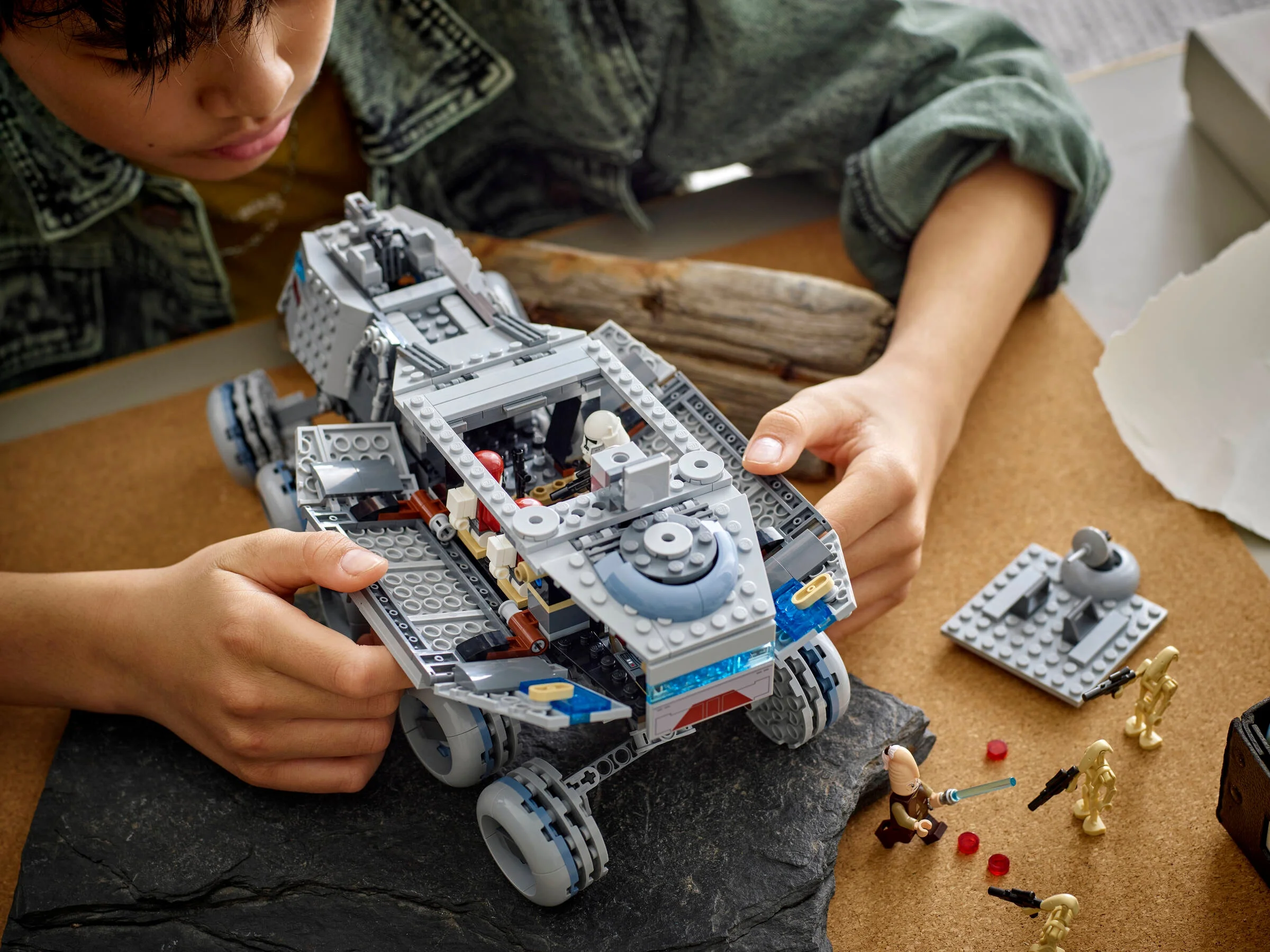 Copil construind Juggernaut-ul Republicii. Include minifigurine și detalii ale vehiculului.
