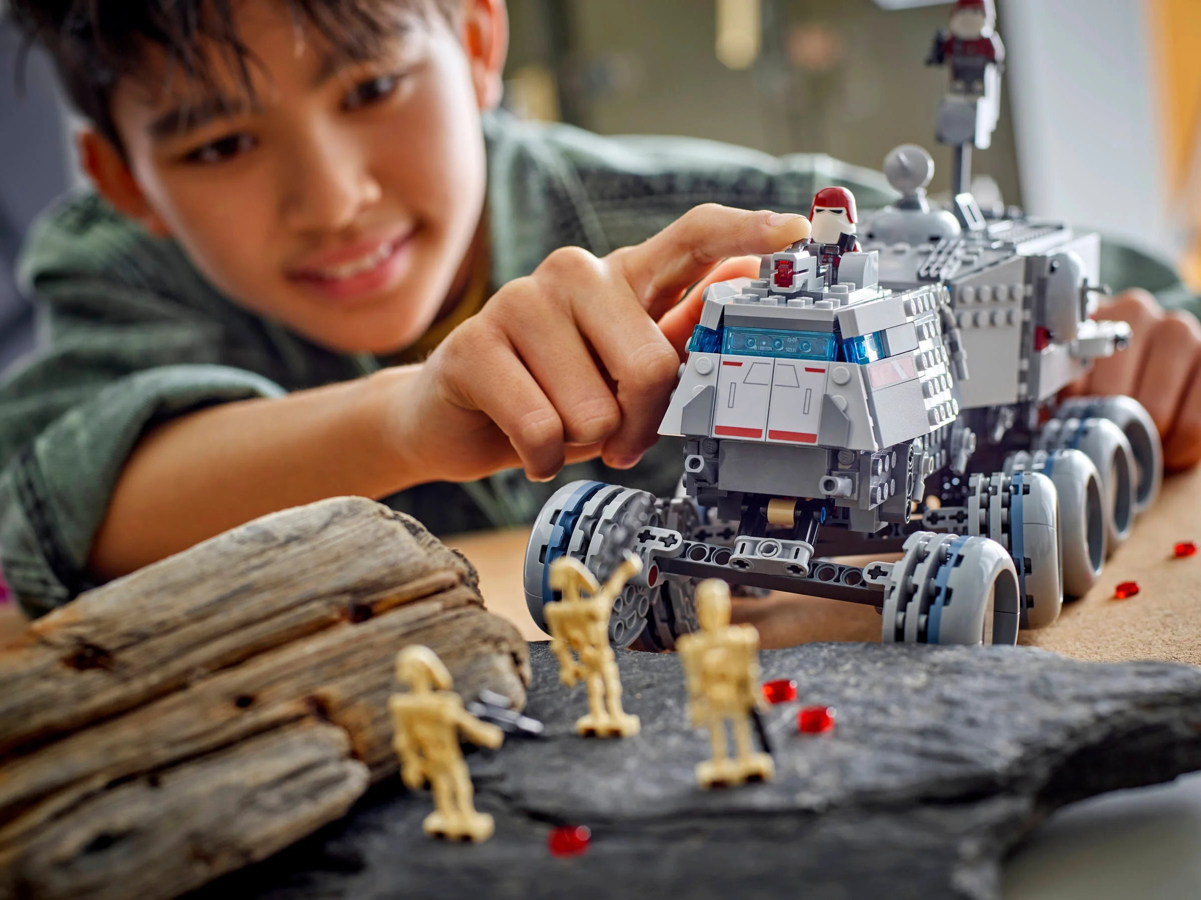 Copil se joacă cu Juggernaut-ul Republicii LEGO Star Wars 75413. Un transport blindat pe roți, cu minifigurine.