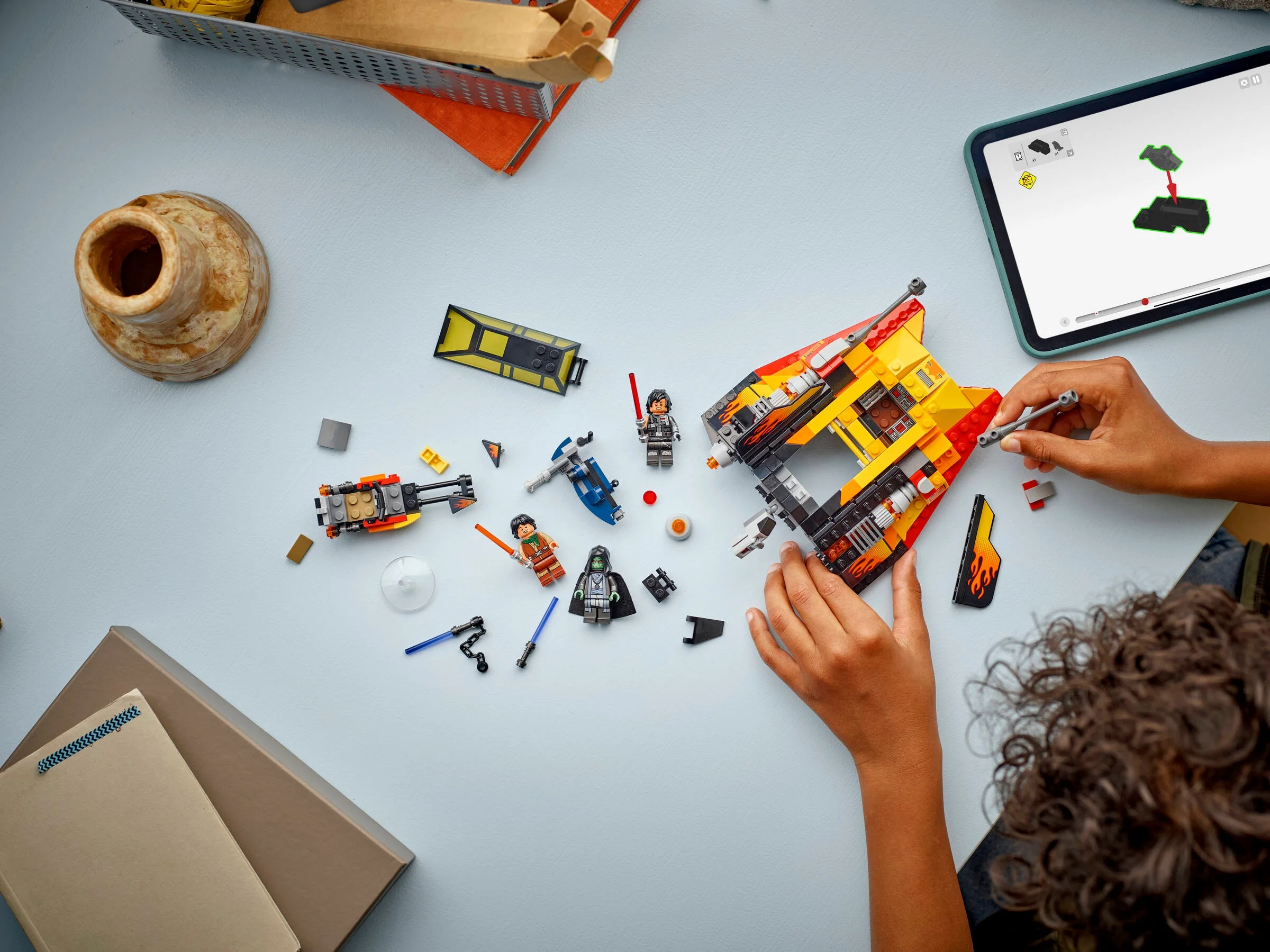 Construirea Snowspeeder-ului LEGO Star Wars cu instrucțiuni pe tabletă. Elemente împrăștiate pe masă.