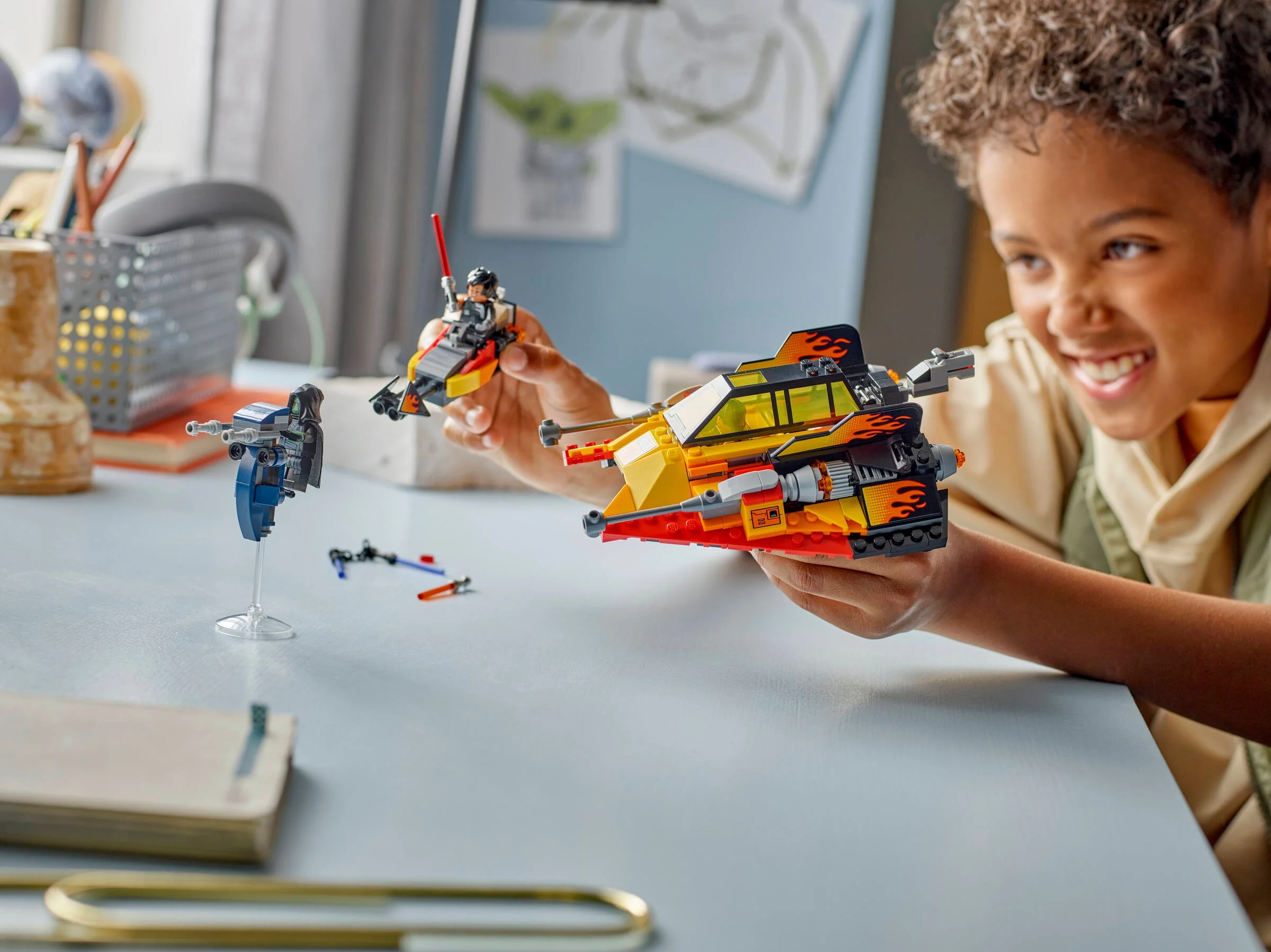 Copil se joacă cu Snowspeeder-ul Force Burner LEGO Star Wars. Are un zâmbet larg, e fericit.