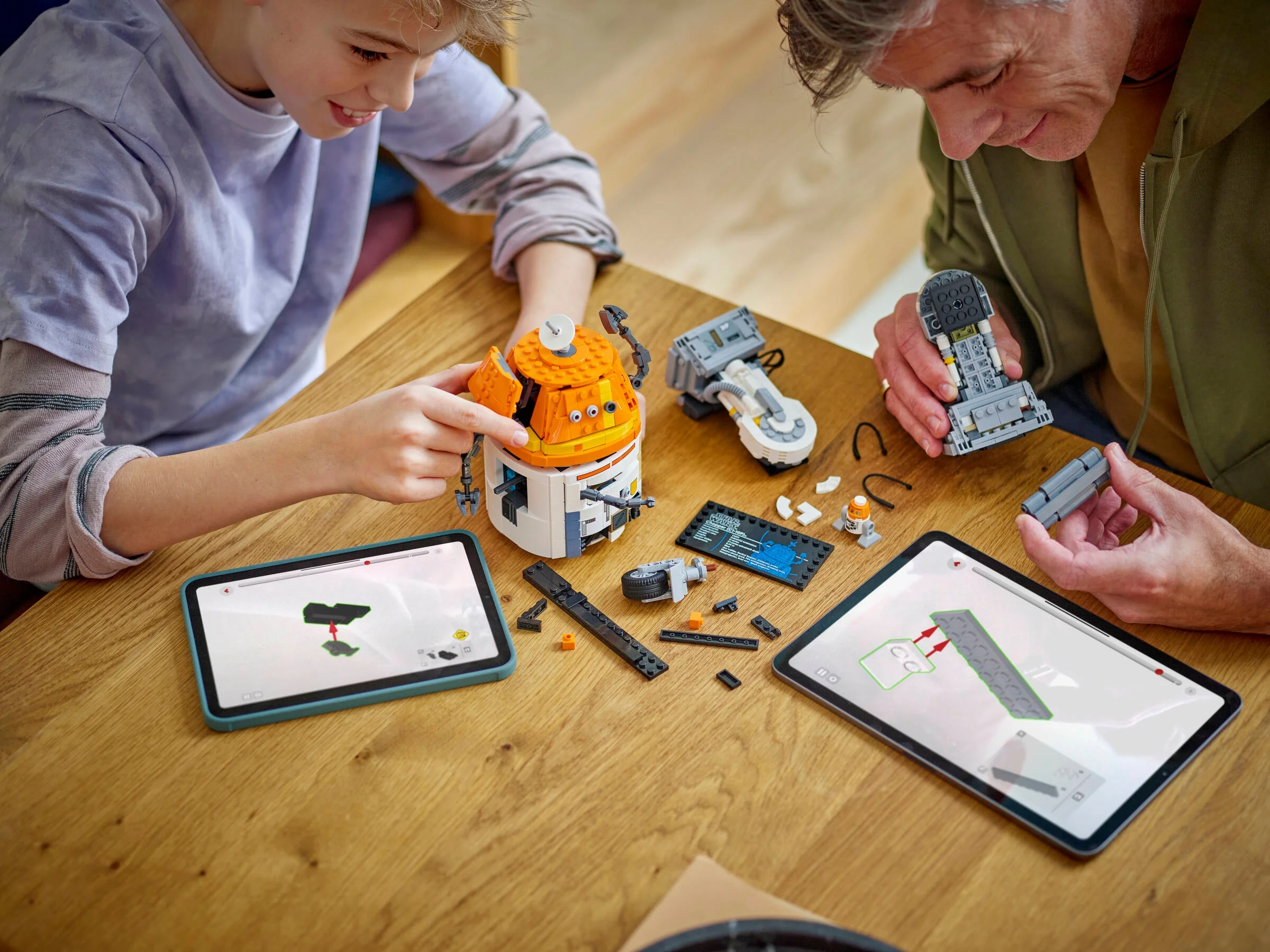 Un băiat și un adult construiesc LEGO Chopper folosind instrucțiuni digitale pe tabletă.
