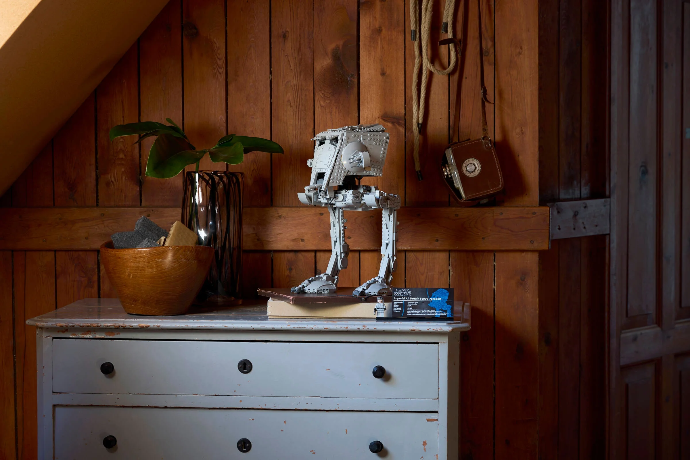 AT-ST LEGO Star Wars pe o comodă, ambient rustic. Un model detaliat expus.