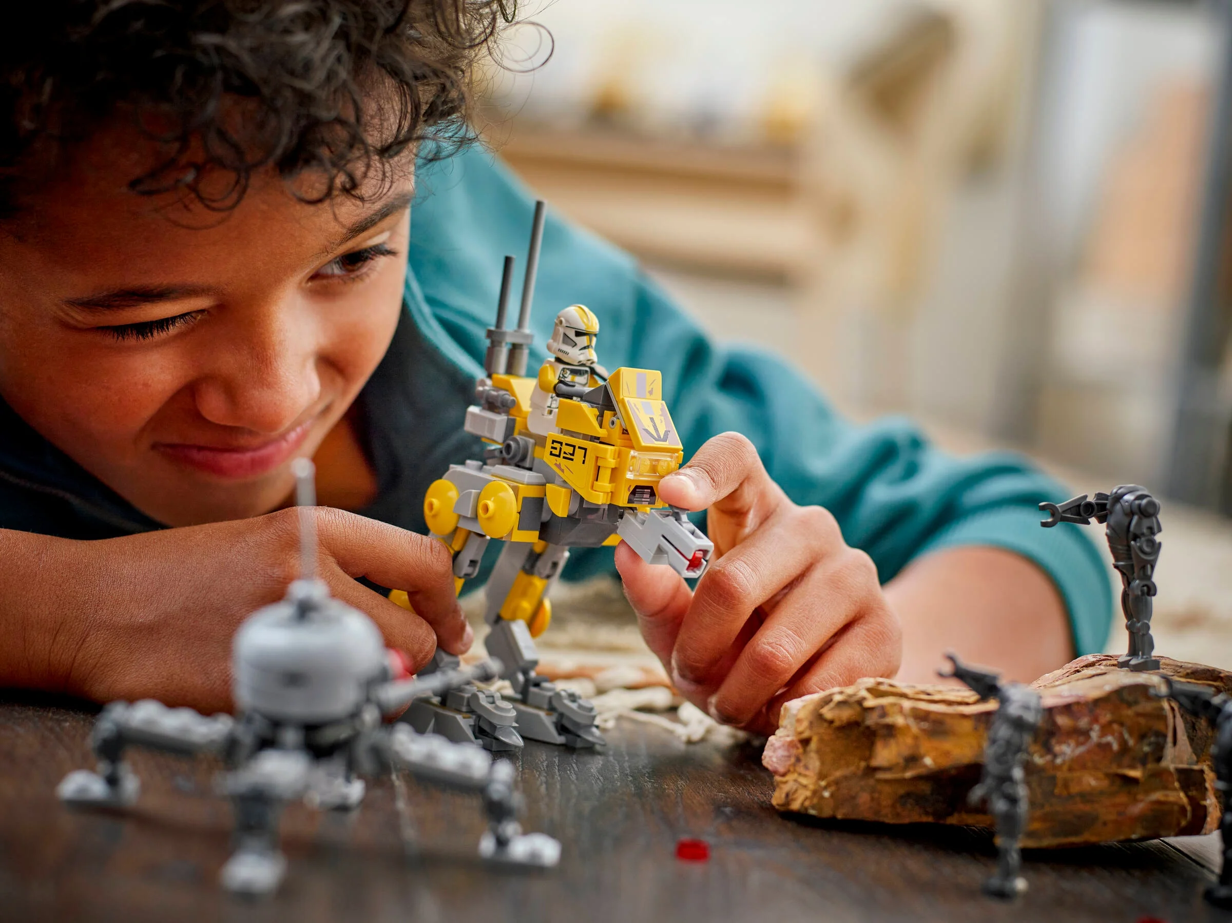 Băiat zâmbitor se joacă cu AT-RT-ul și droizii din setul LEGO Star Wars 75431.