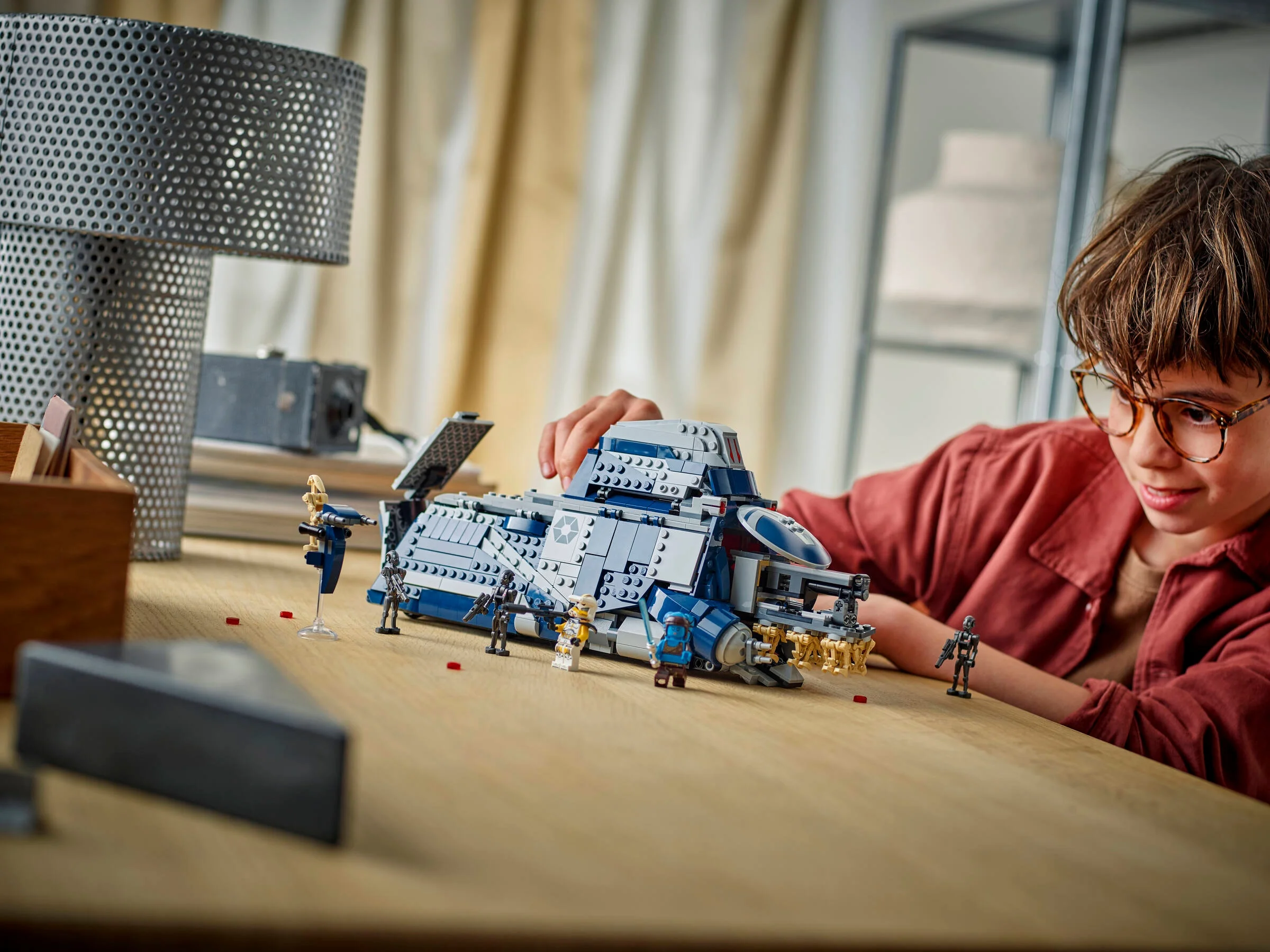 Un copil se joacă cu setul LEGO 75435 Bătălia de pe Felucia. Modelul MTT e central, cu minifigurine.