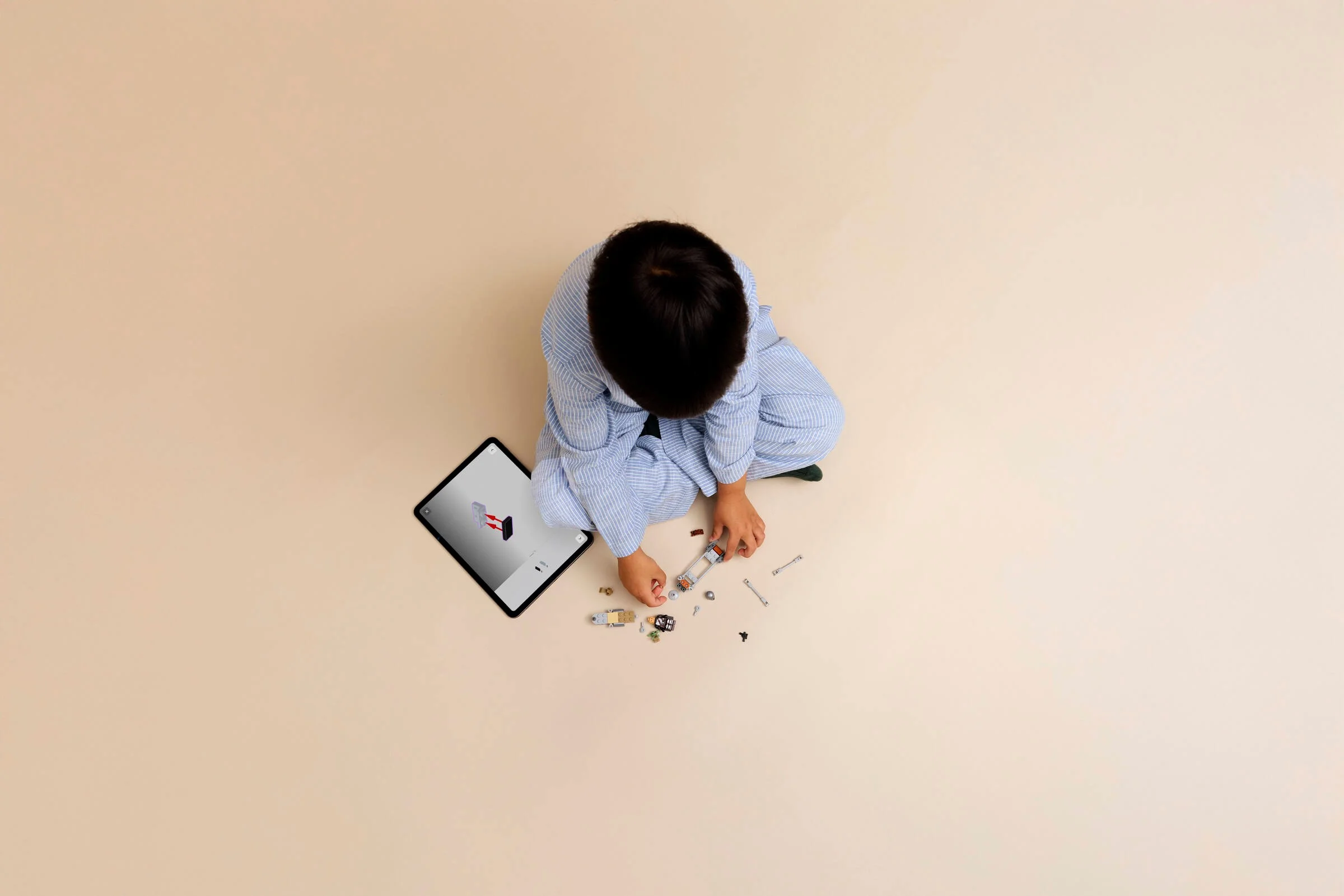 Copil construind un model LEGO cu instrucțiuni digitale pe tabletă. Joacă-te creativ!