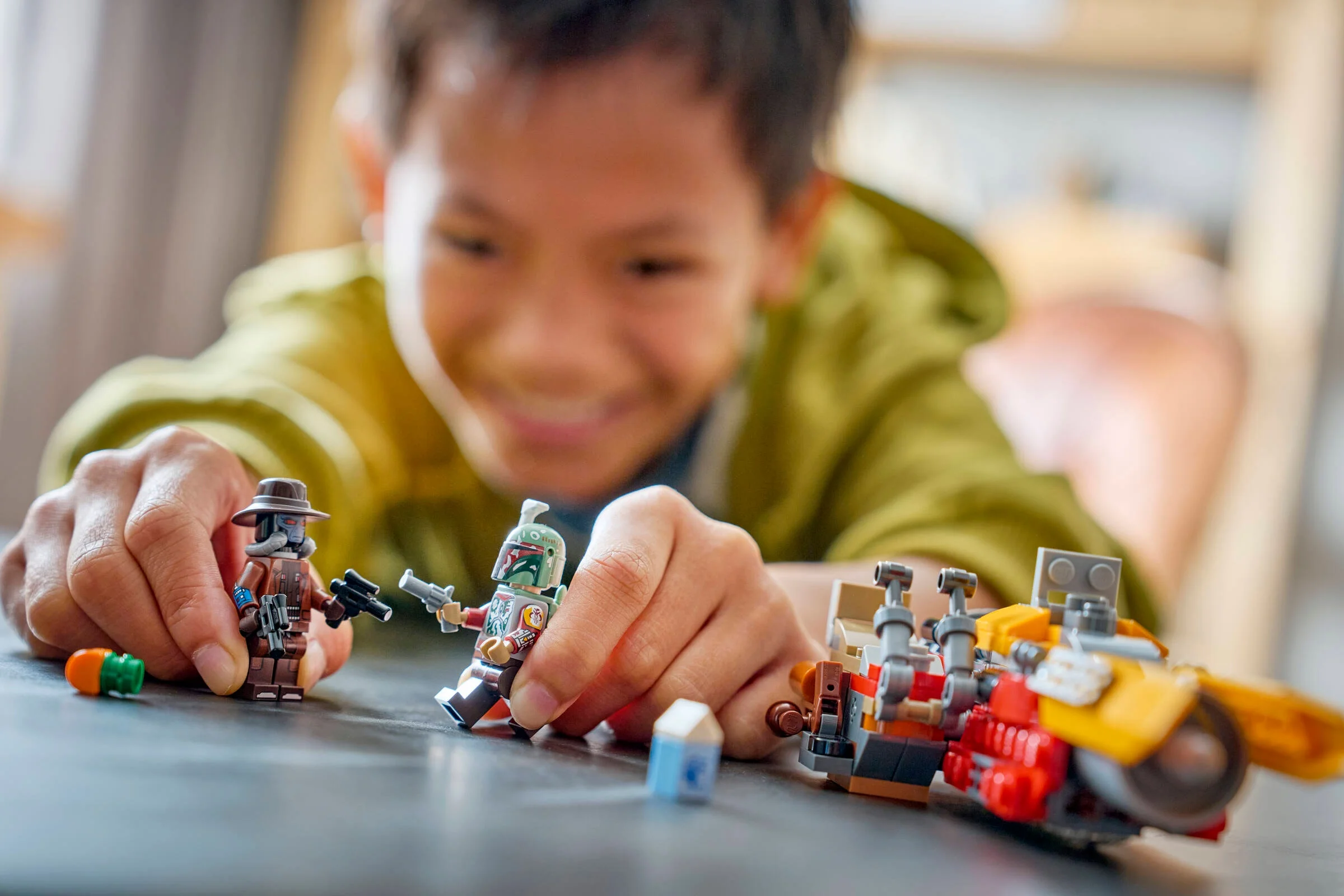 Copil se joacă cu minifigurinele și speederul LEGO Cobb Vanth. Distracție cu setul Star Wars!