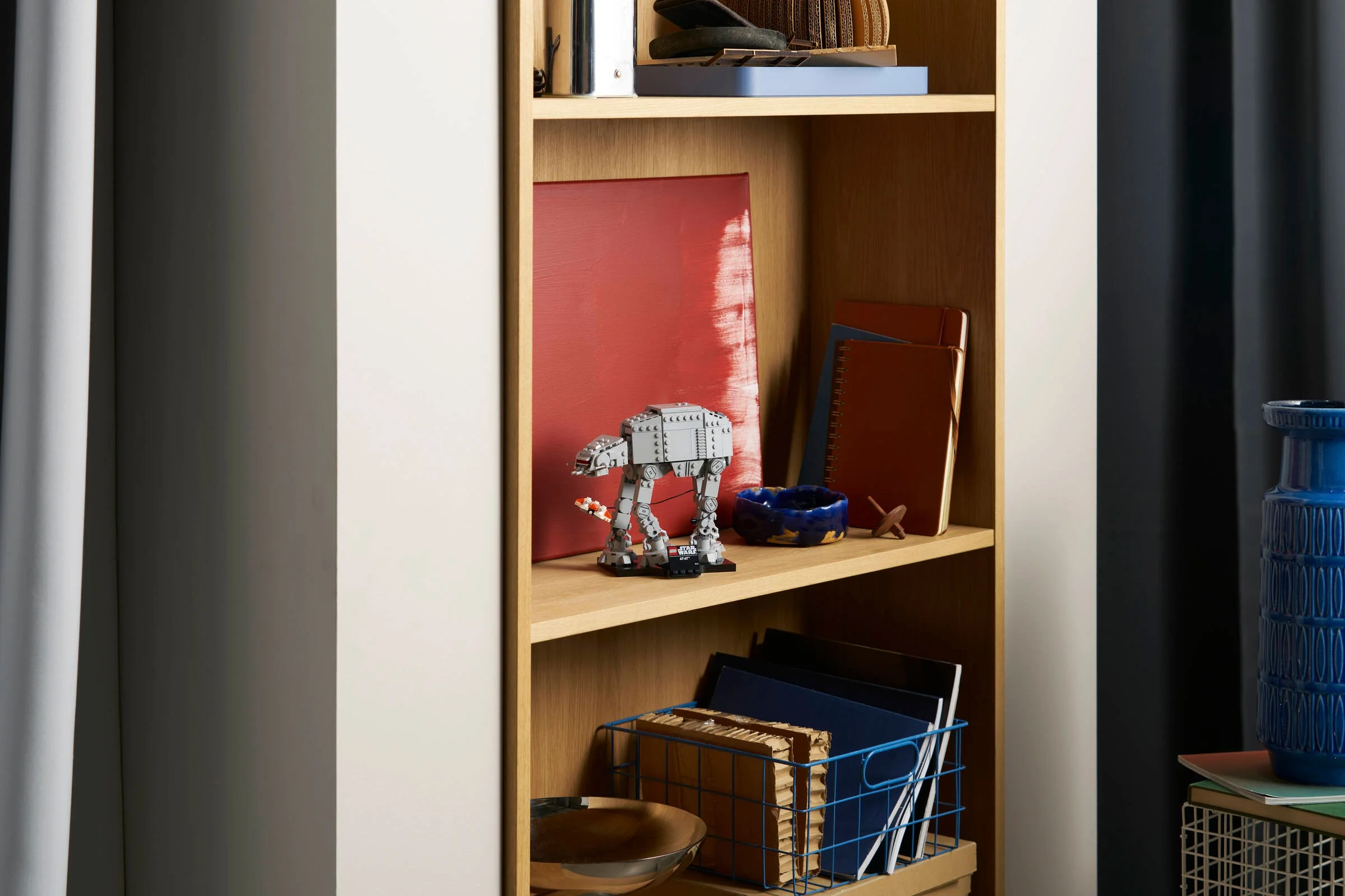 AT-AT LEGO Star Wars expus pe un raft, alături de alte obiecte decorative. Modelul este vizibil parțial.