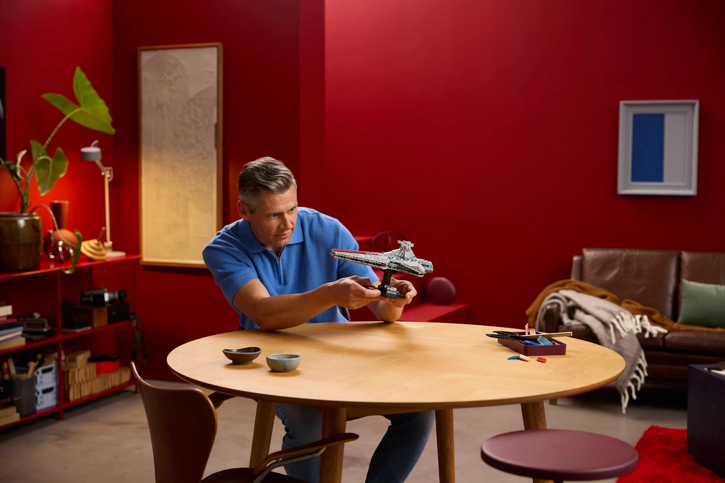 Bărbat ține modelul LEGO Venator. Imagine lifestyle atractivă, bine iluminată.