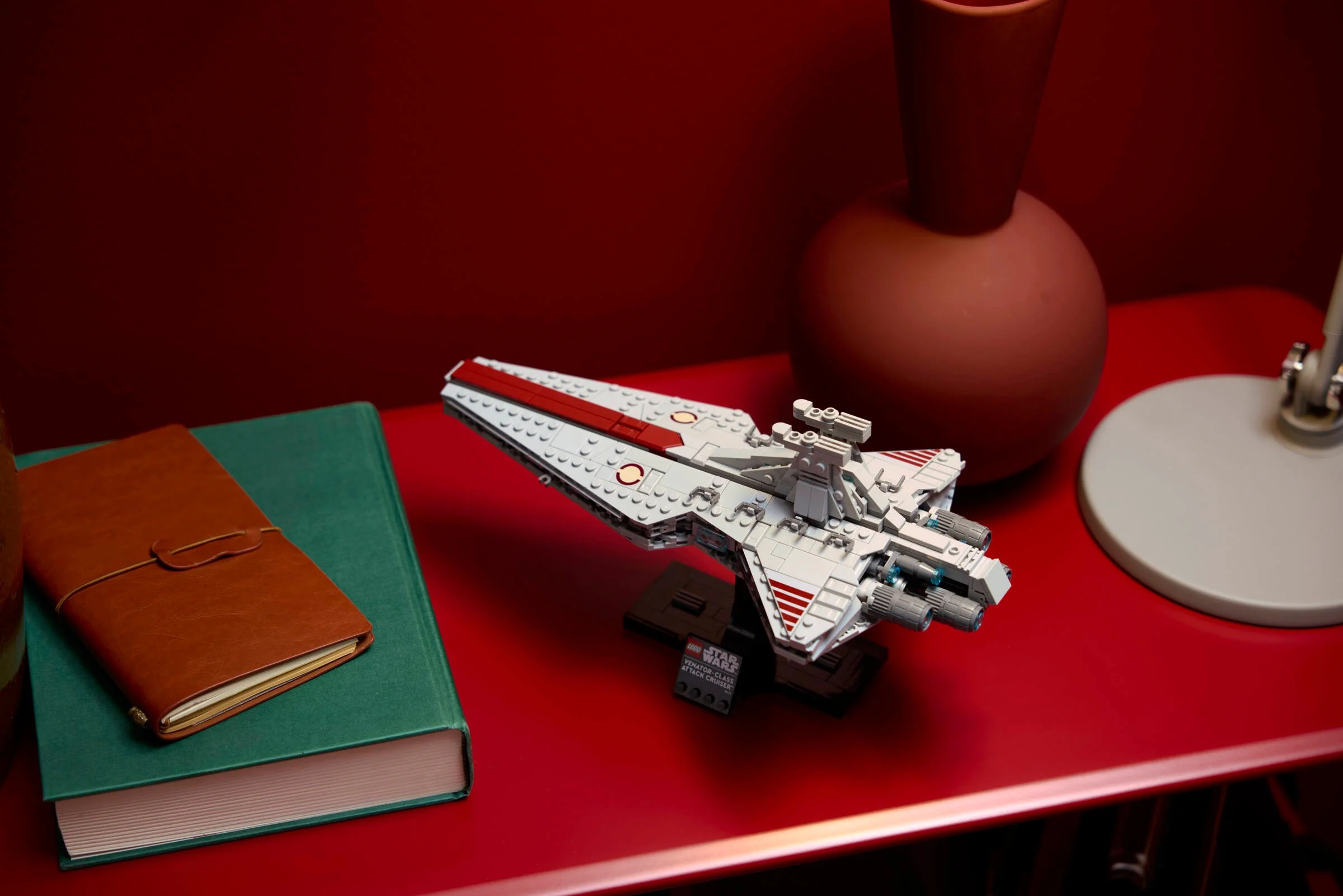 O imagine cu modelul LEGO Venator-class Attack Cruiser, stilizat pe o masă roșie.