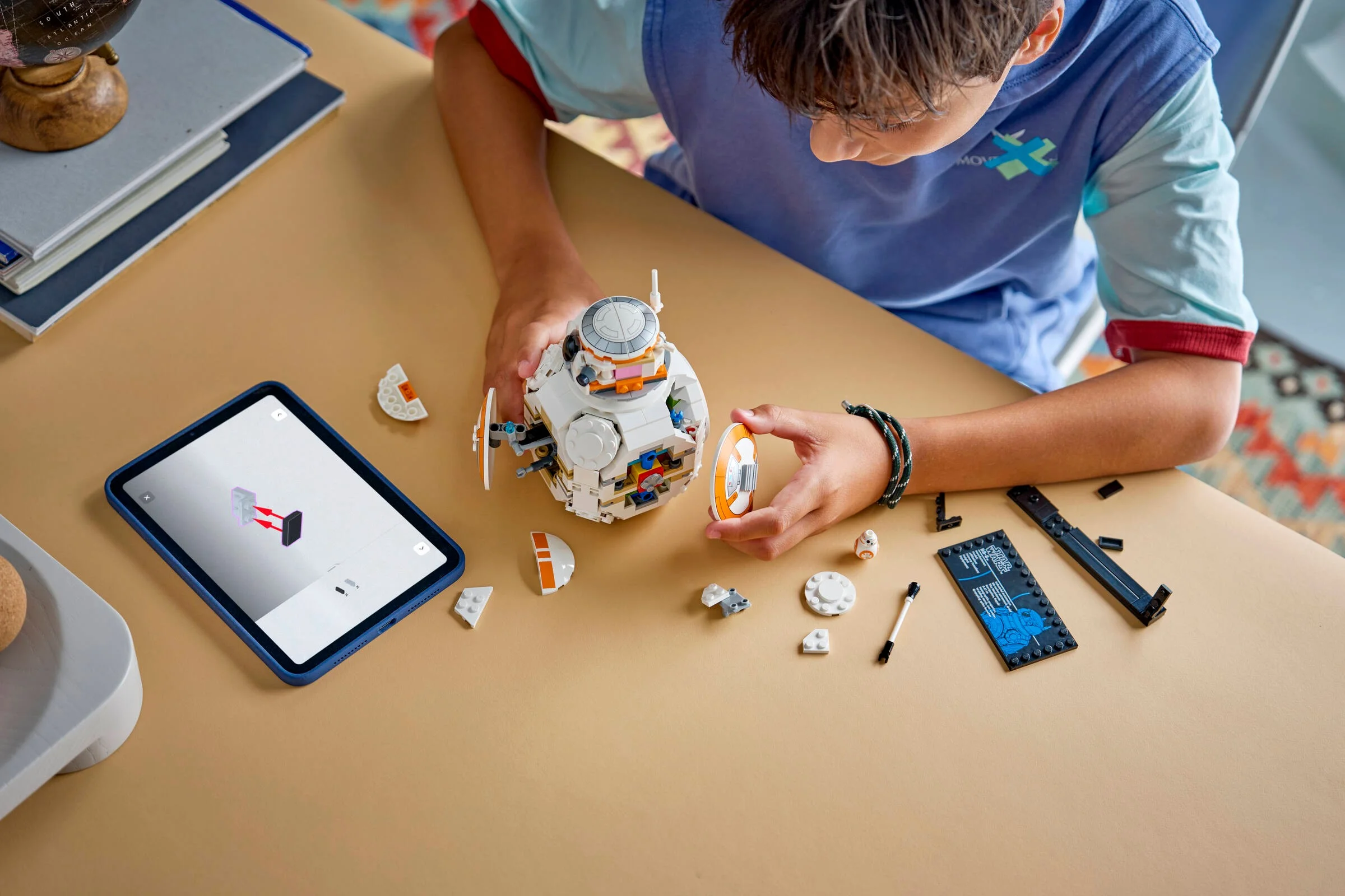Imagine cu un copil construind BB-8 cu instrucțiuni digitale pe tabletă. Joc creativ și interactiv.