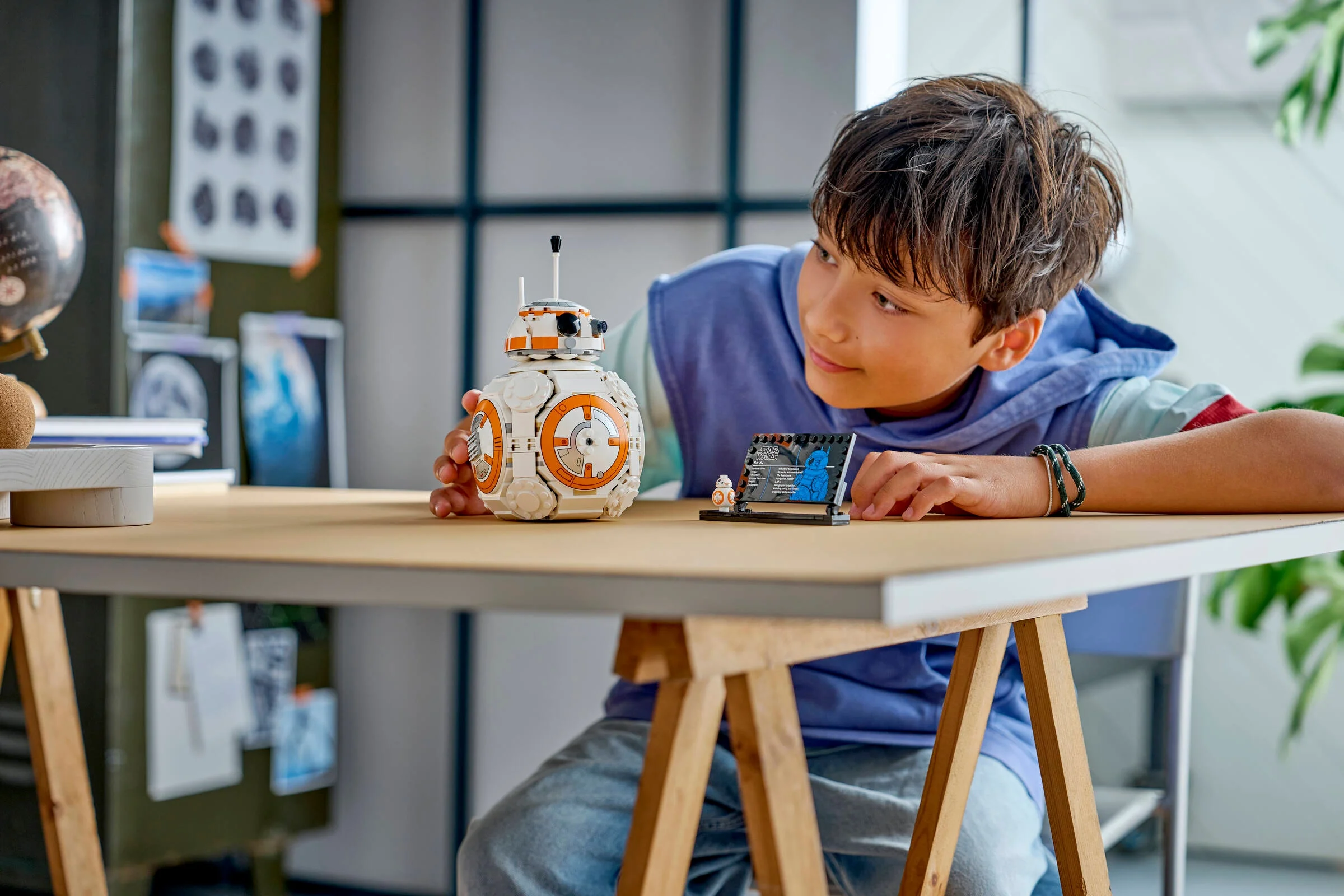 Copilul admiră modelul LEGO BB-8 și placa cu informații. O imagine inspirațională.
