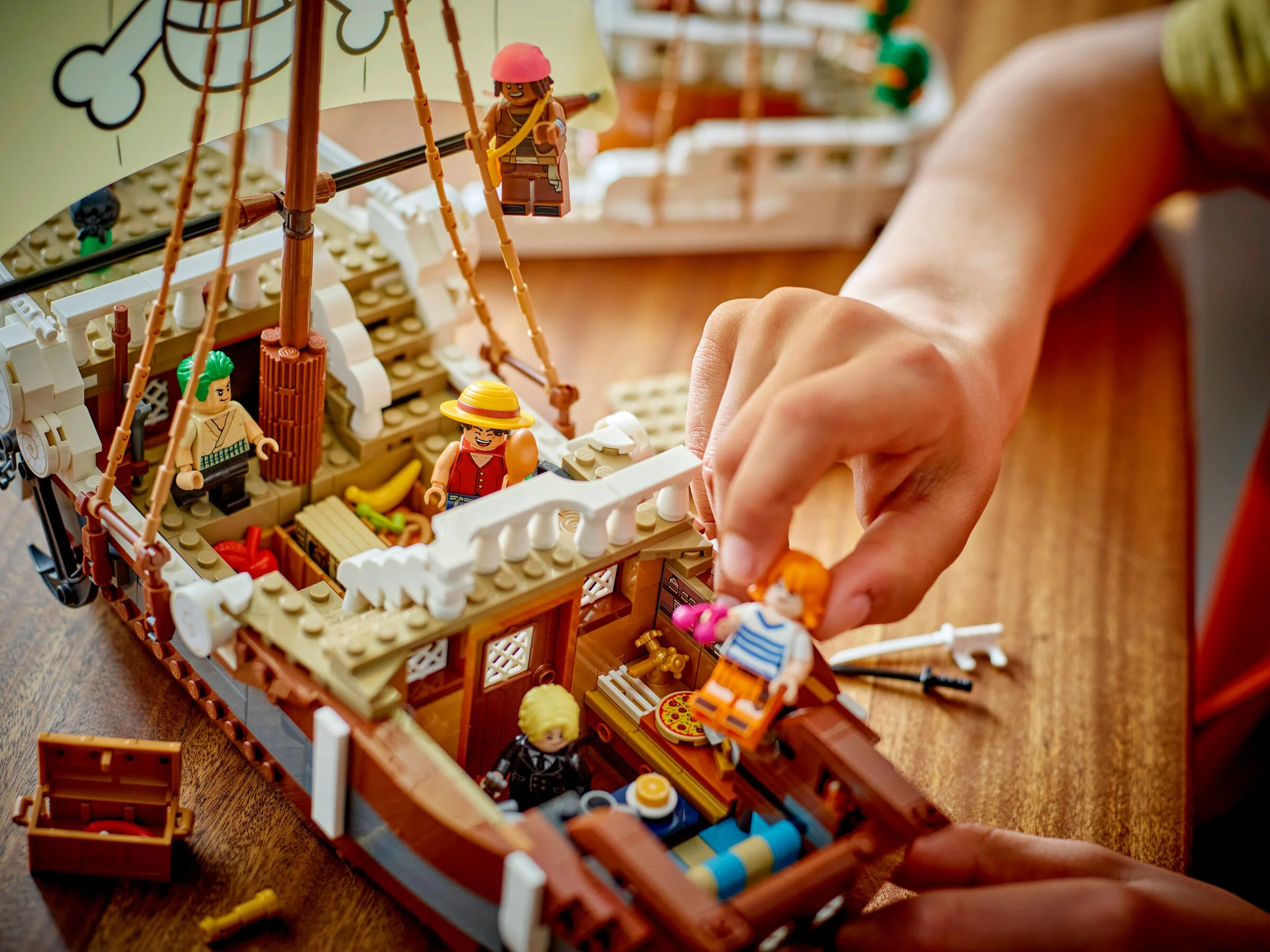 Imagine cu o persoană care se joacă cu corabia Going Merry LEGO, detaliind interiorul și minifigurinele.