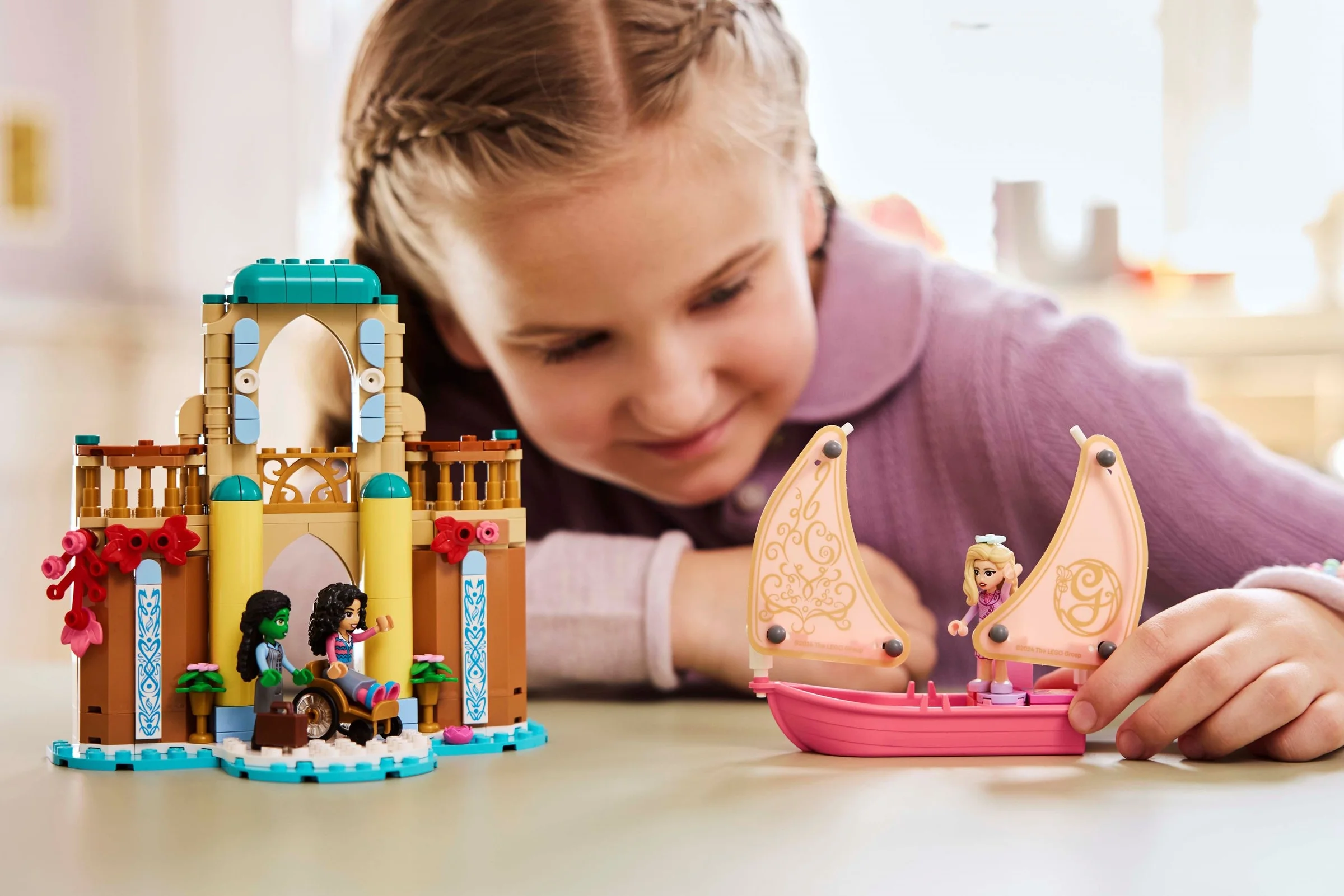 Fetiță se joacă cu setul LEGO Wicked: Glinda, Elphaba și Nessarose la Universitatea Shiz.