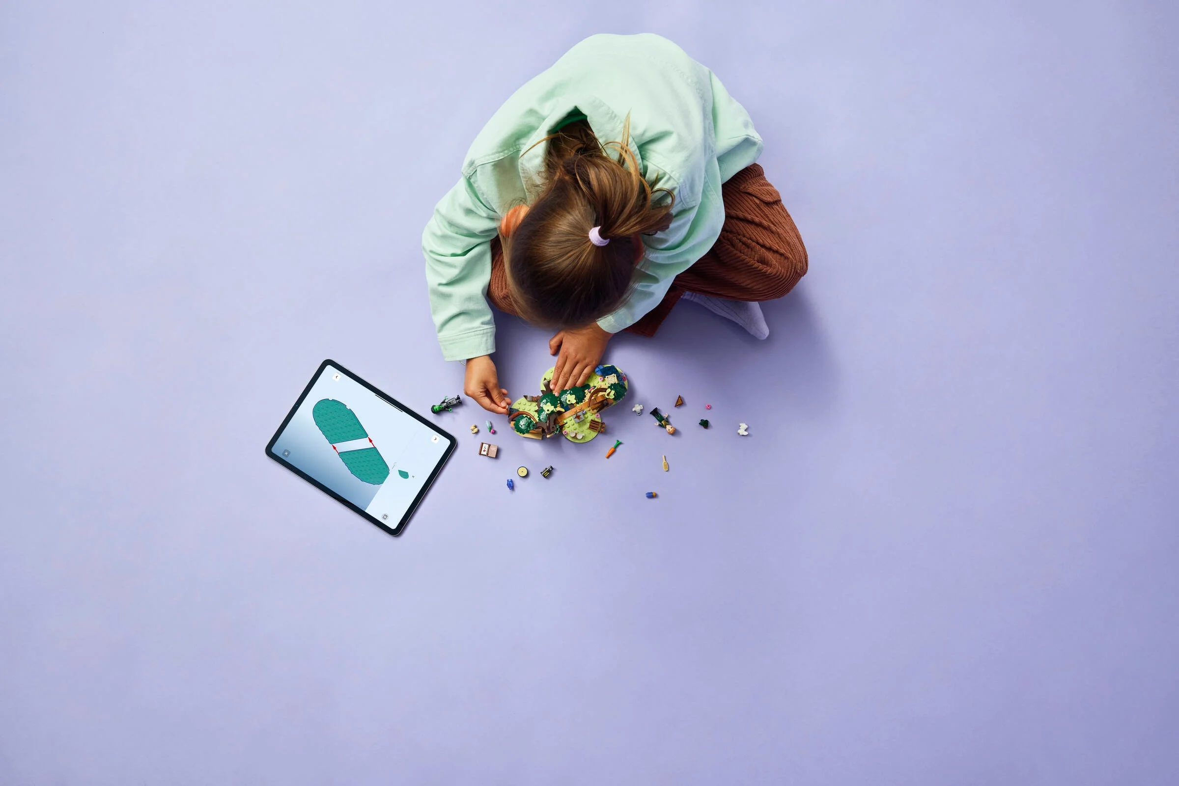Copil construind setul LEGO Elphaba's Retreat folosind instrucțiuni digitale pe tabletă.