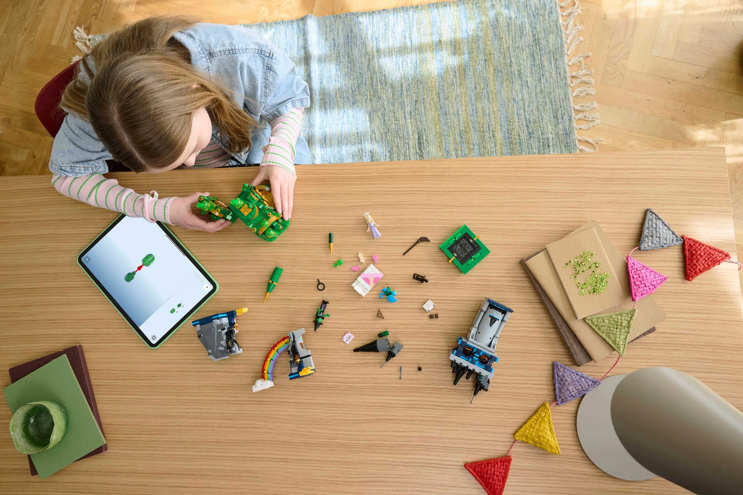 O fată construiește castelul LEGO Emerald City cu instrucțiuni digitale pe tabletă.