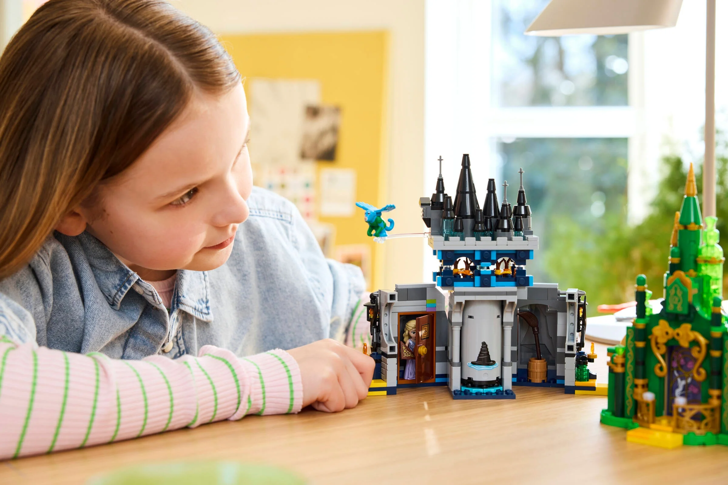 O fată se joacă cu setul LEGO 75689, cu Castelul Kiamo Ko și Orașul Smarald.