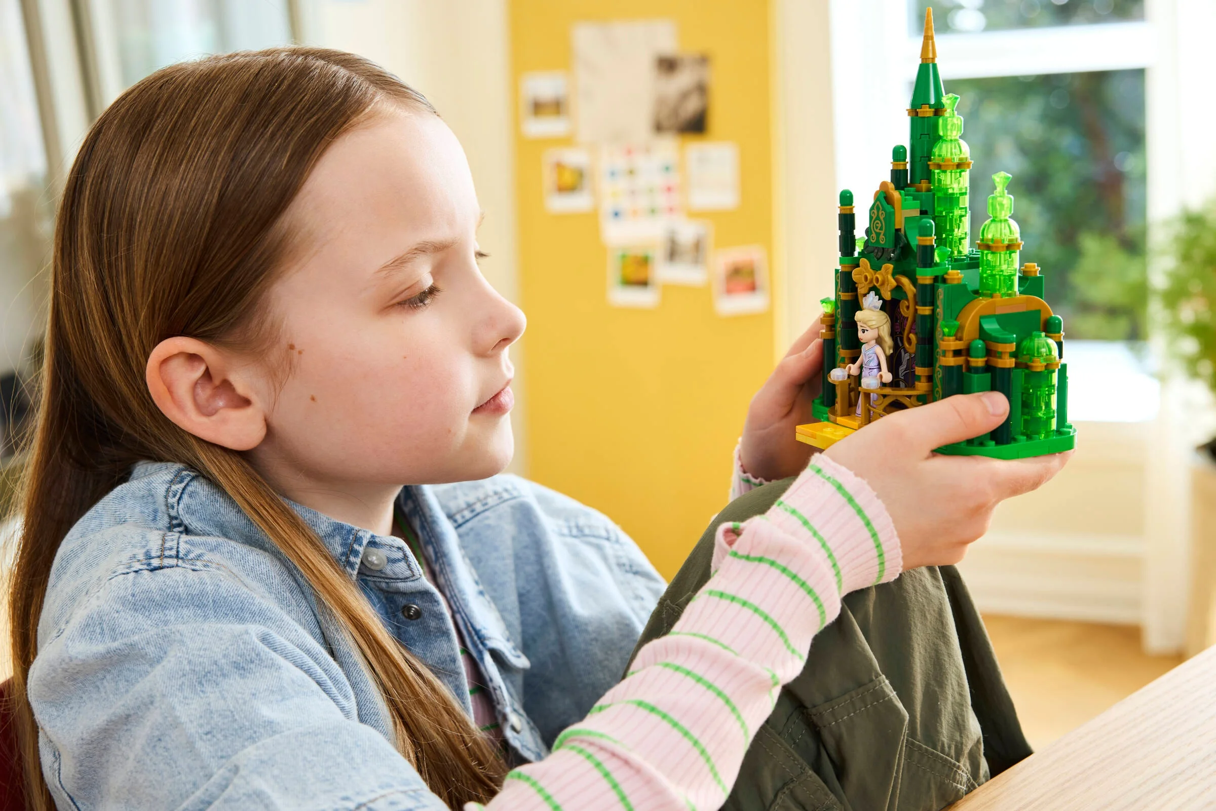 Fetiță admirând Castelul de Smarald LEGO. O scenă de joacă creativă și captivantă.