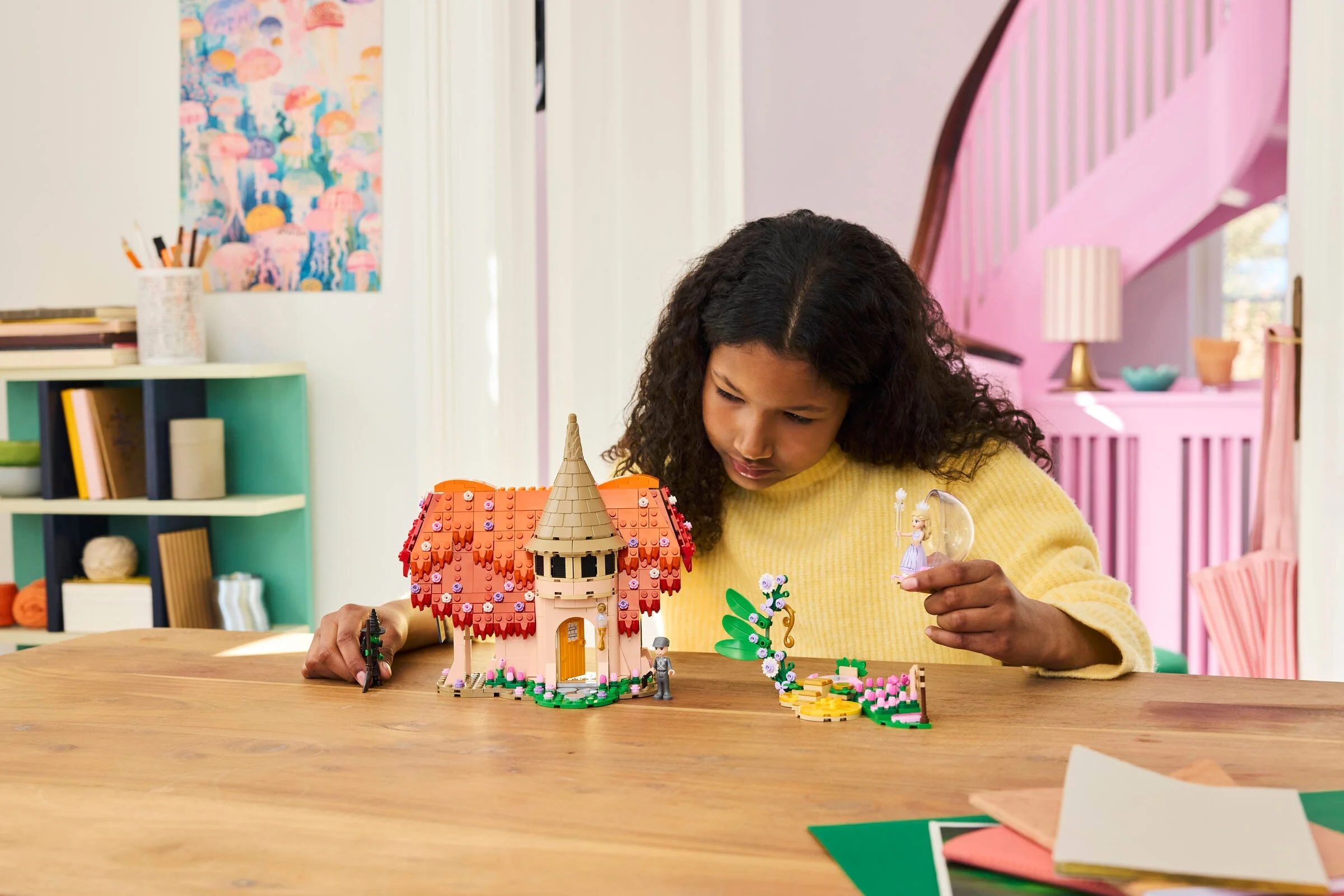 Fetiță se joacă cu setul LEGO Munchkinland. Vedere apropiată pe căsuță și personaje.