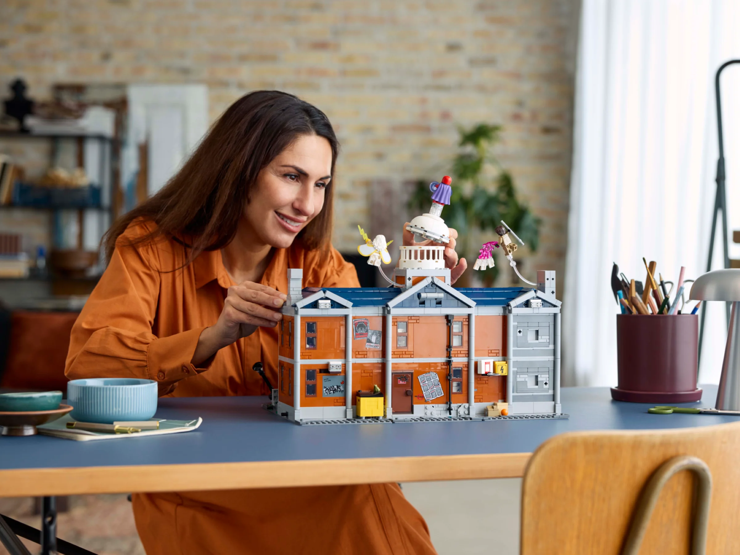 Femeie construind X-Mansion LEGO. Imagine detaliată, atrăgătoare, cu culori calde.