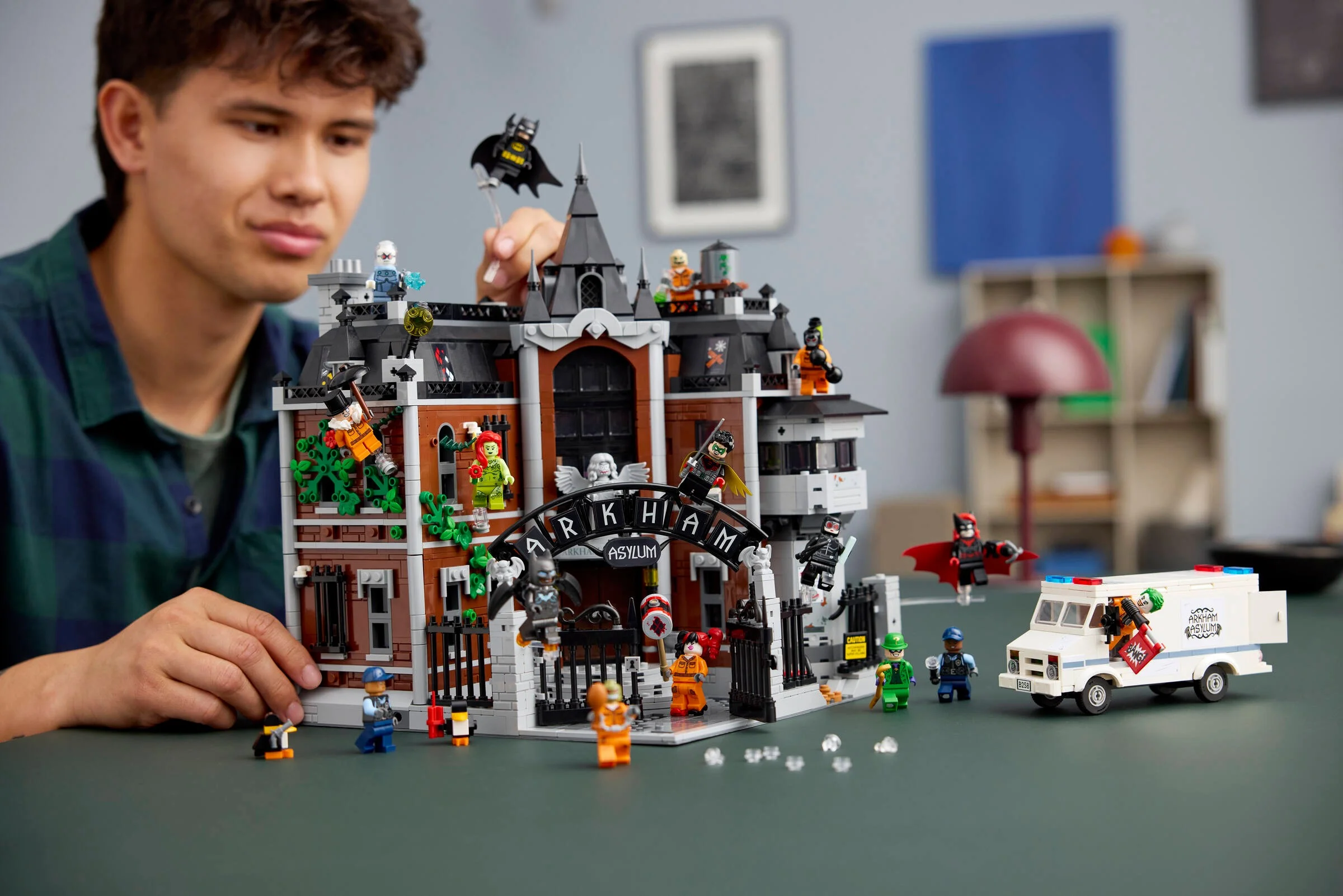 Un tânăr interacționează cu setul LEGO Arkham Asylum, prezentând modelul finalizat.