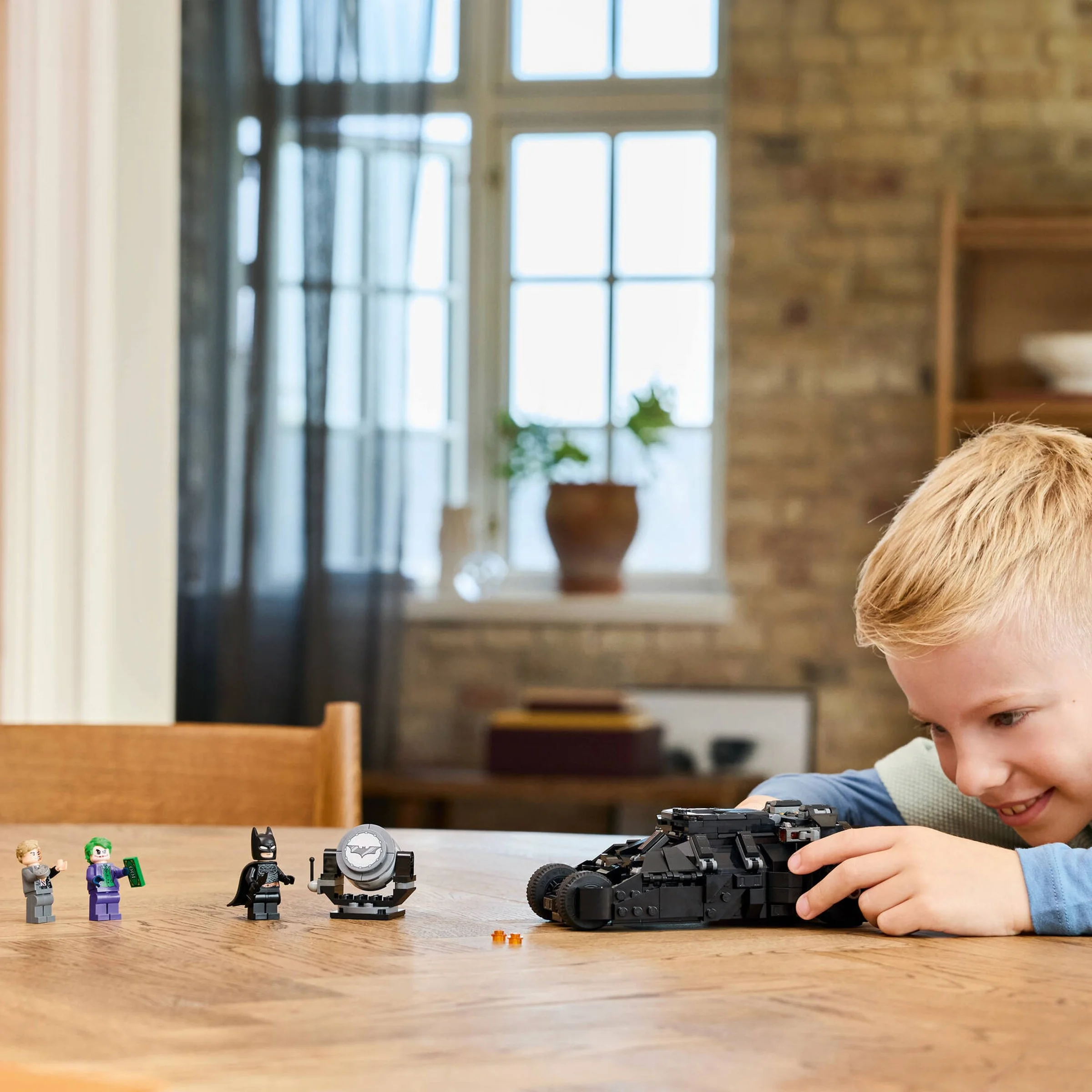 Băiat se joacă cu LEGO Batman Tumbler, setul 76303. Minifigurine incluse.