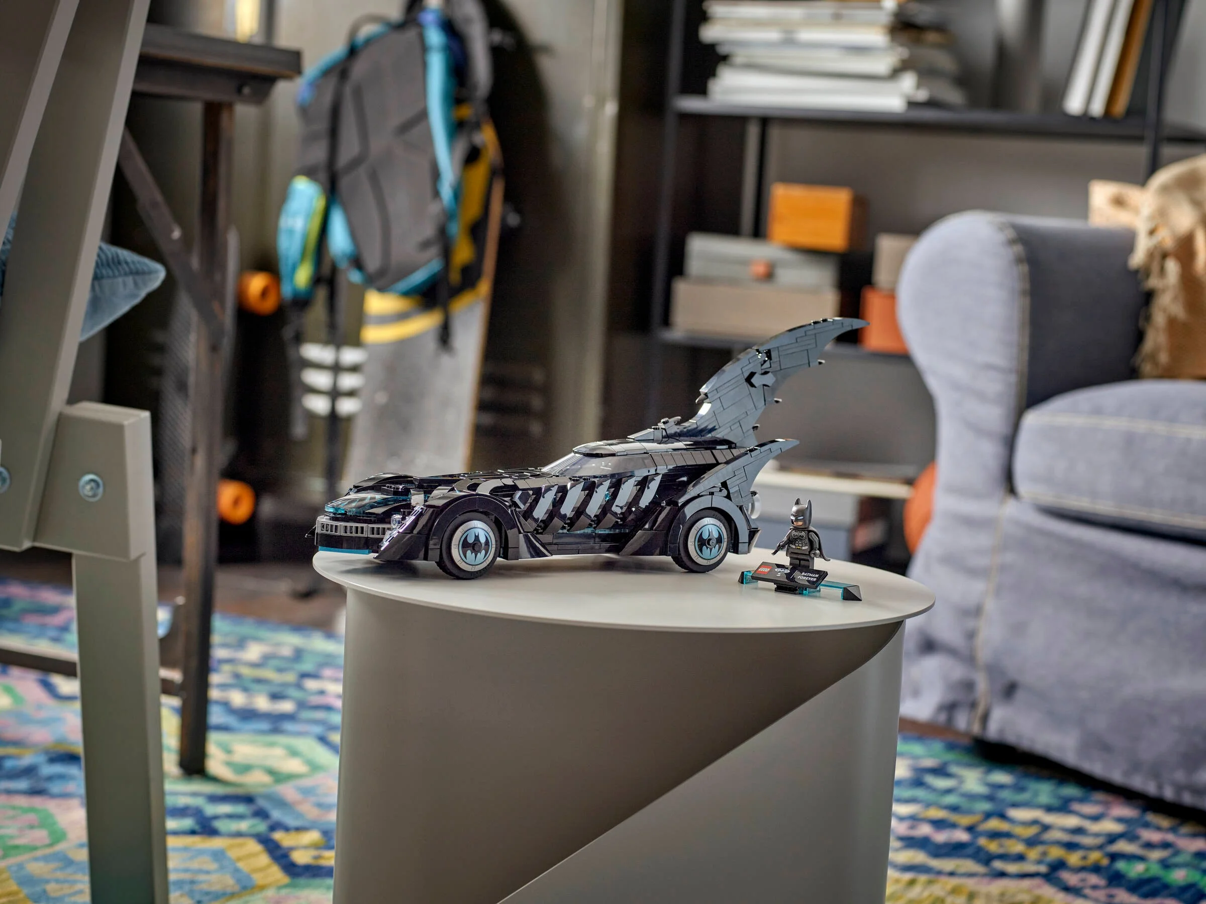 Imagine cu Batmobilul LEGO 76304 din Batman Forever și minifigurina Batman, prezentate într-un cadru ambiental.