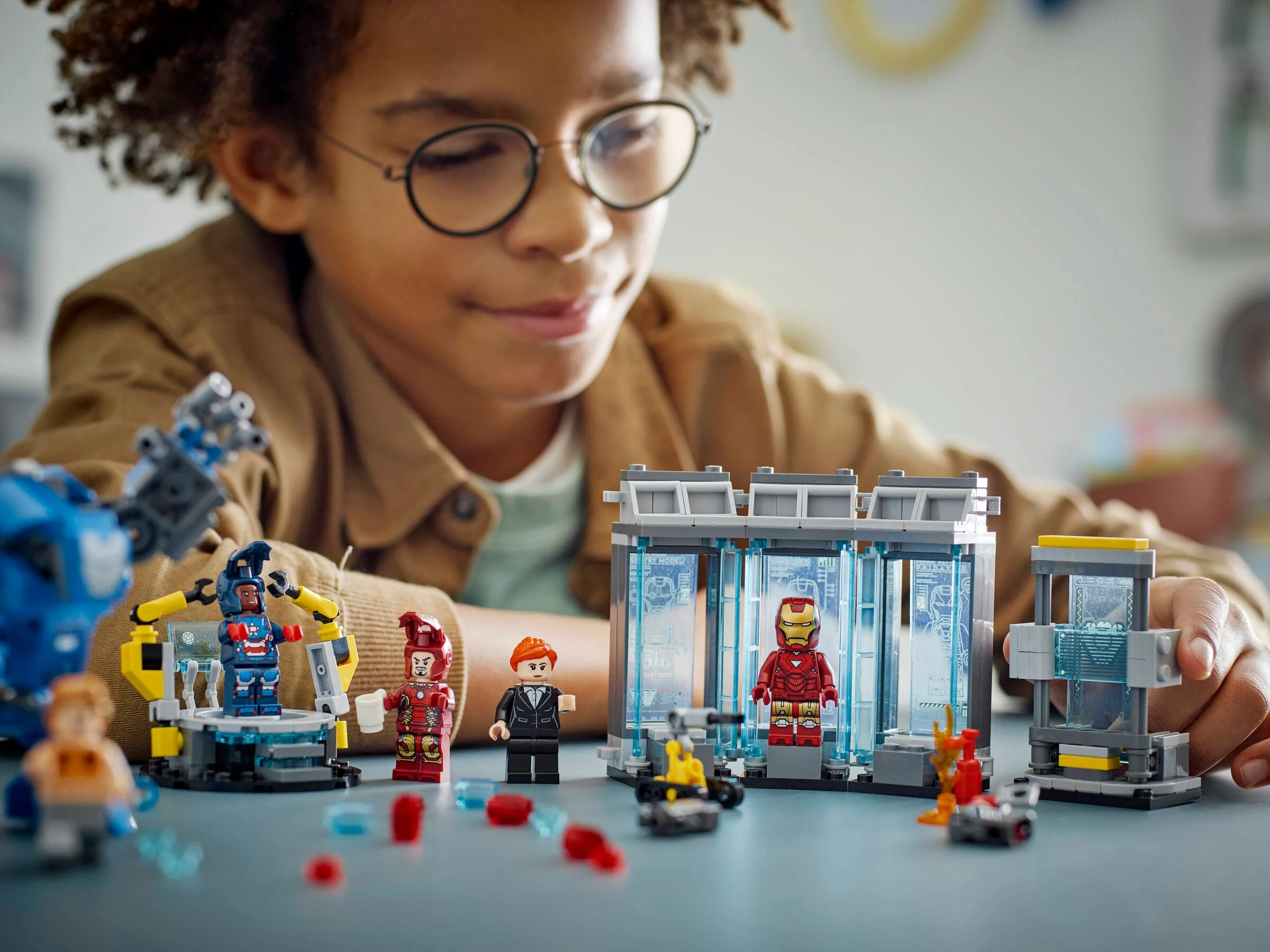 Copil se joacă cu Laboratorul lui Iron Man LEGO 76315, Hall of Armor, un set detaliat.