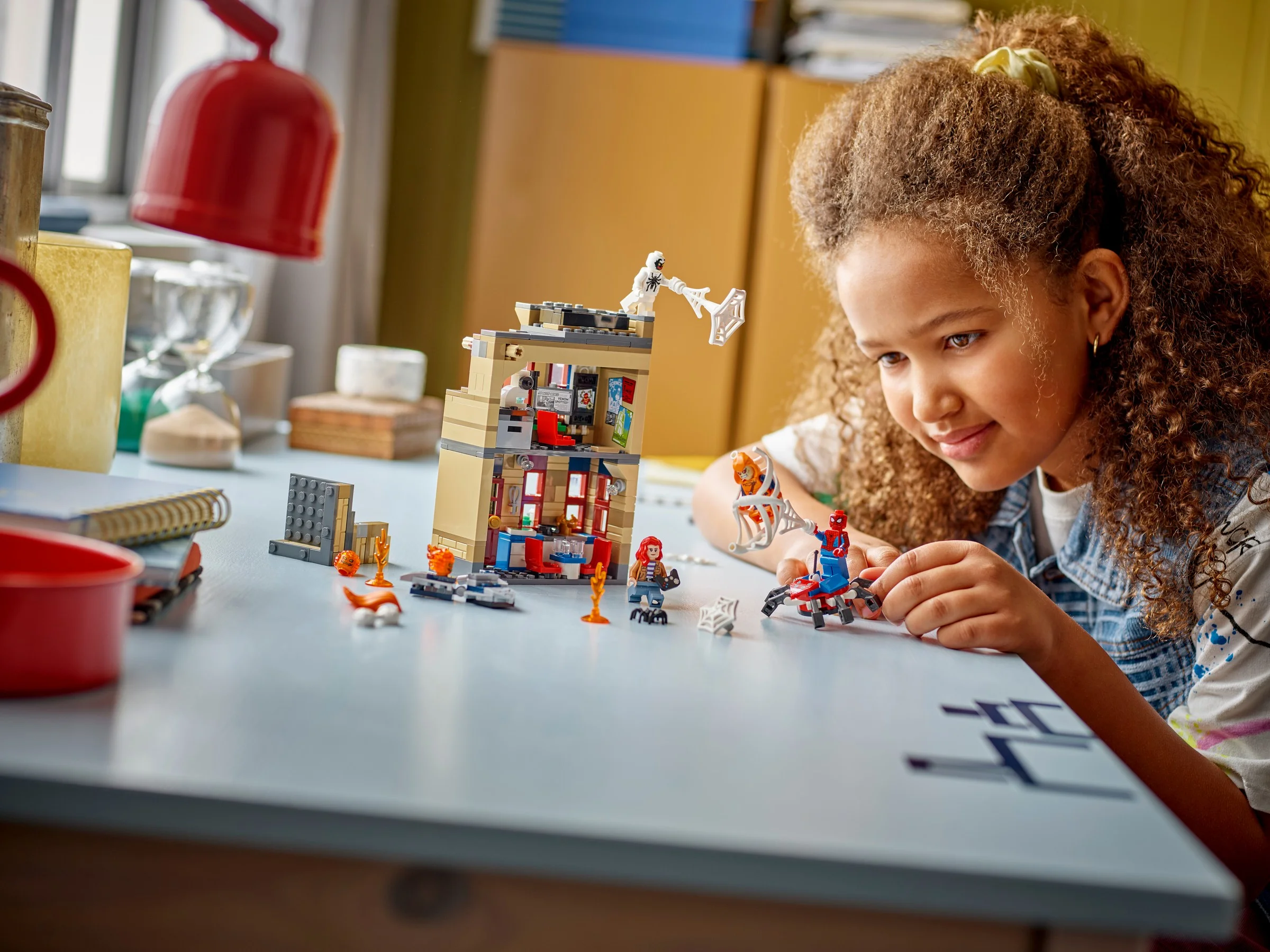 Fetiță se joacă cu setul LEGO 76317, explorând apartamentul lui Peter Parker. O scenă plină de imaginație.