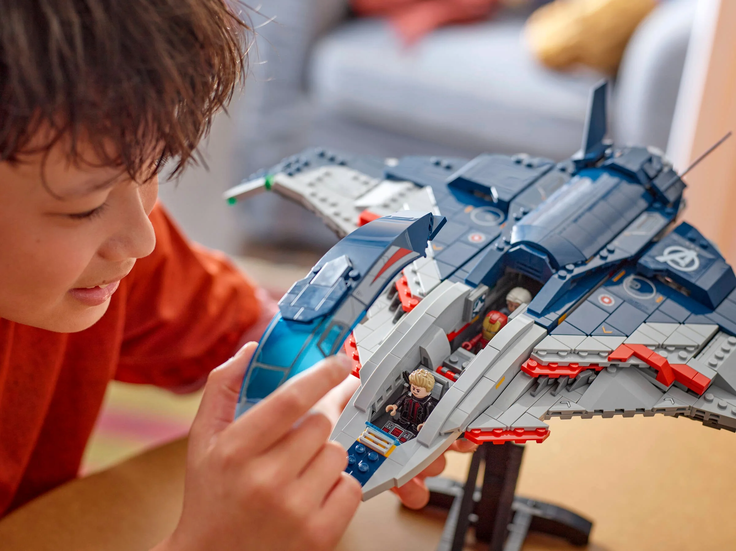 Băiat se joacă cu Quinjet-ul Avengers, explorând cabina și mini-figurinele incluse.