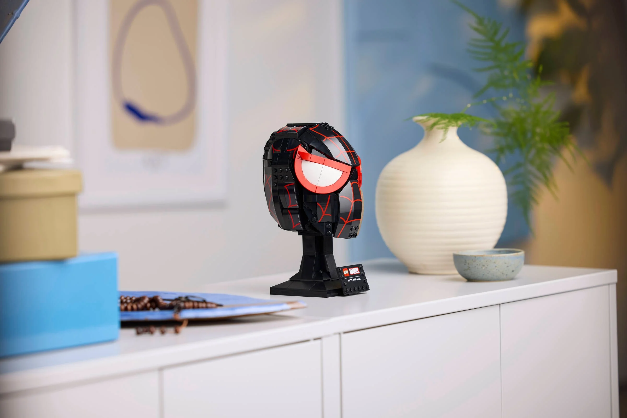 Mască LEGO Miles Morales expusă elegant pe un dulap. Detaliu atrăgător pentru fani.