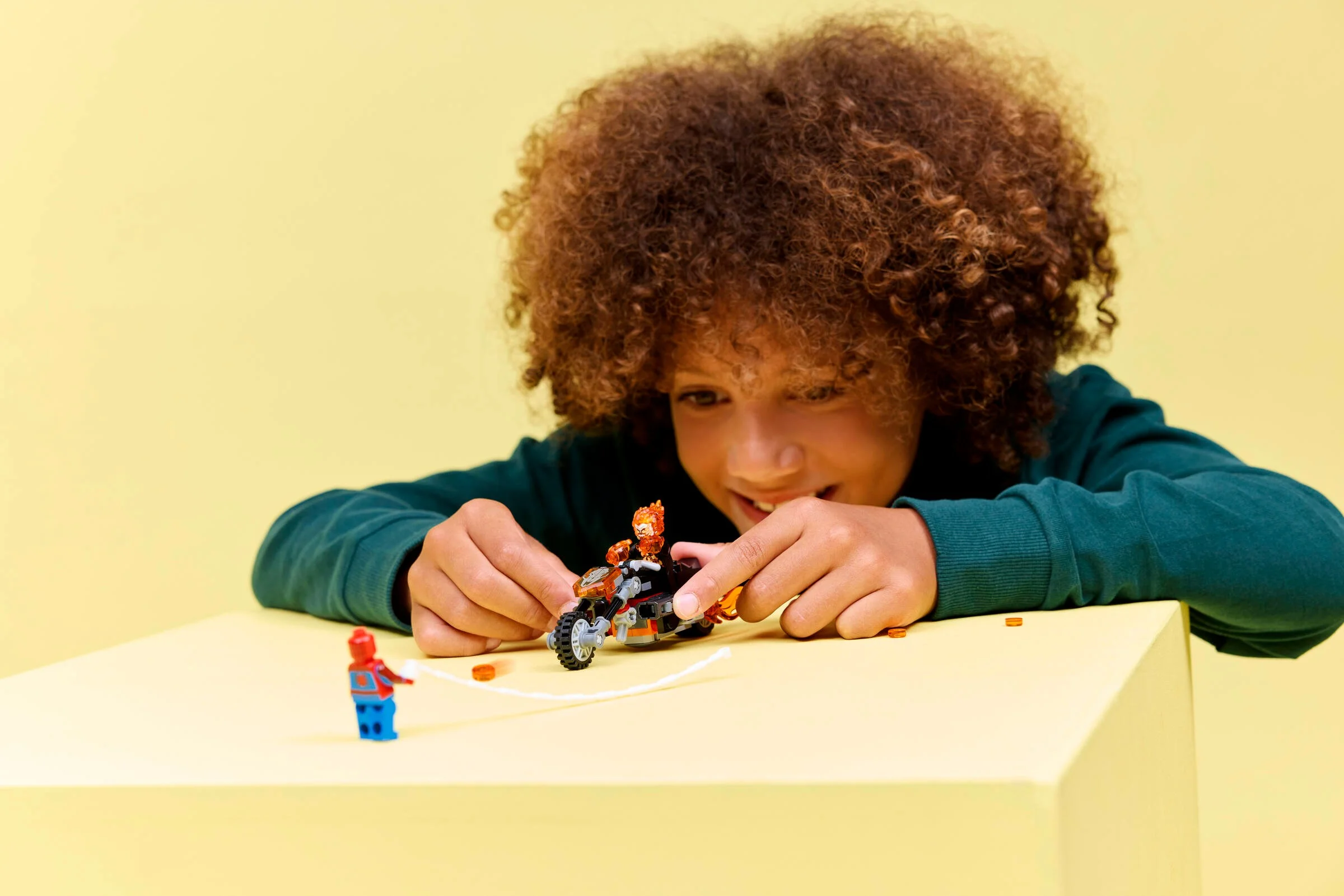 Copil se joacă cu setul LEGO Spider-Man contra Ghost Rider. Distracție cu supereroi și motociclete.