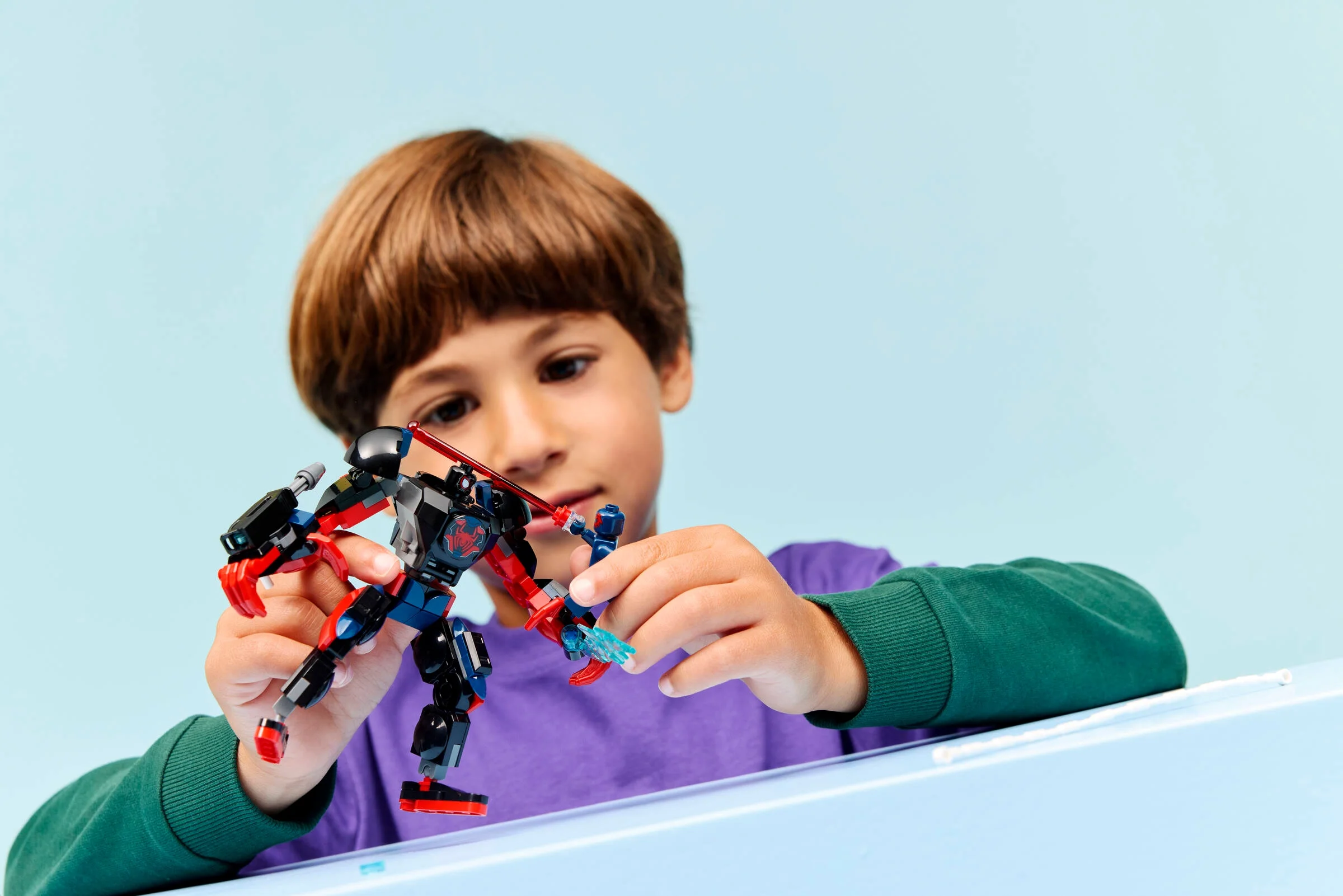Băiat joacă cu setul LEGO 76337, mech-ul lui Miles Morales luptând cu Spider-Man 2099.