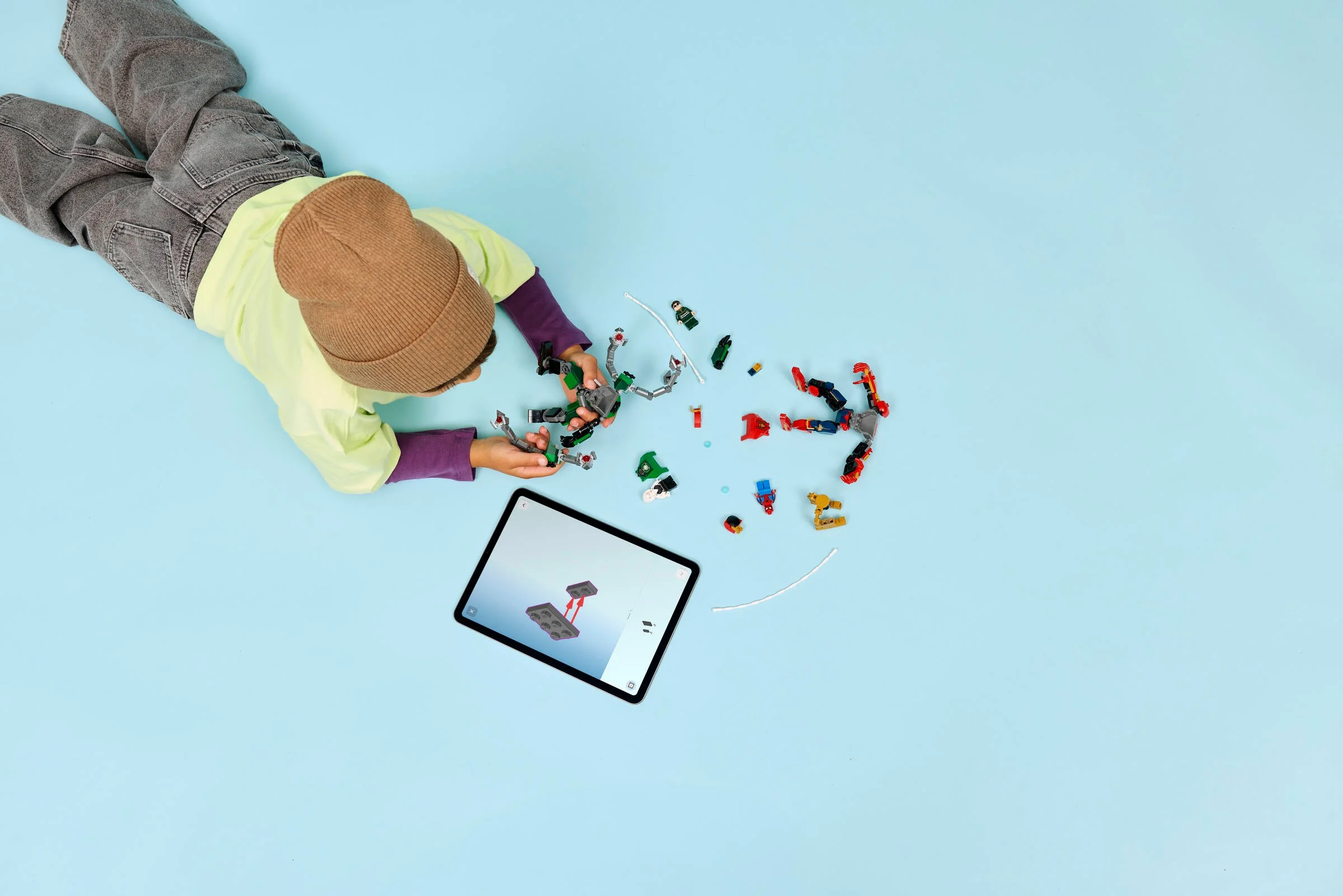 Copil construind setul LEGO 76338 cu ajutorul instrucțiunilor digitale pe tabletă.