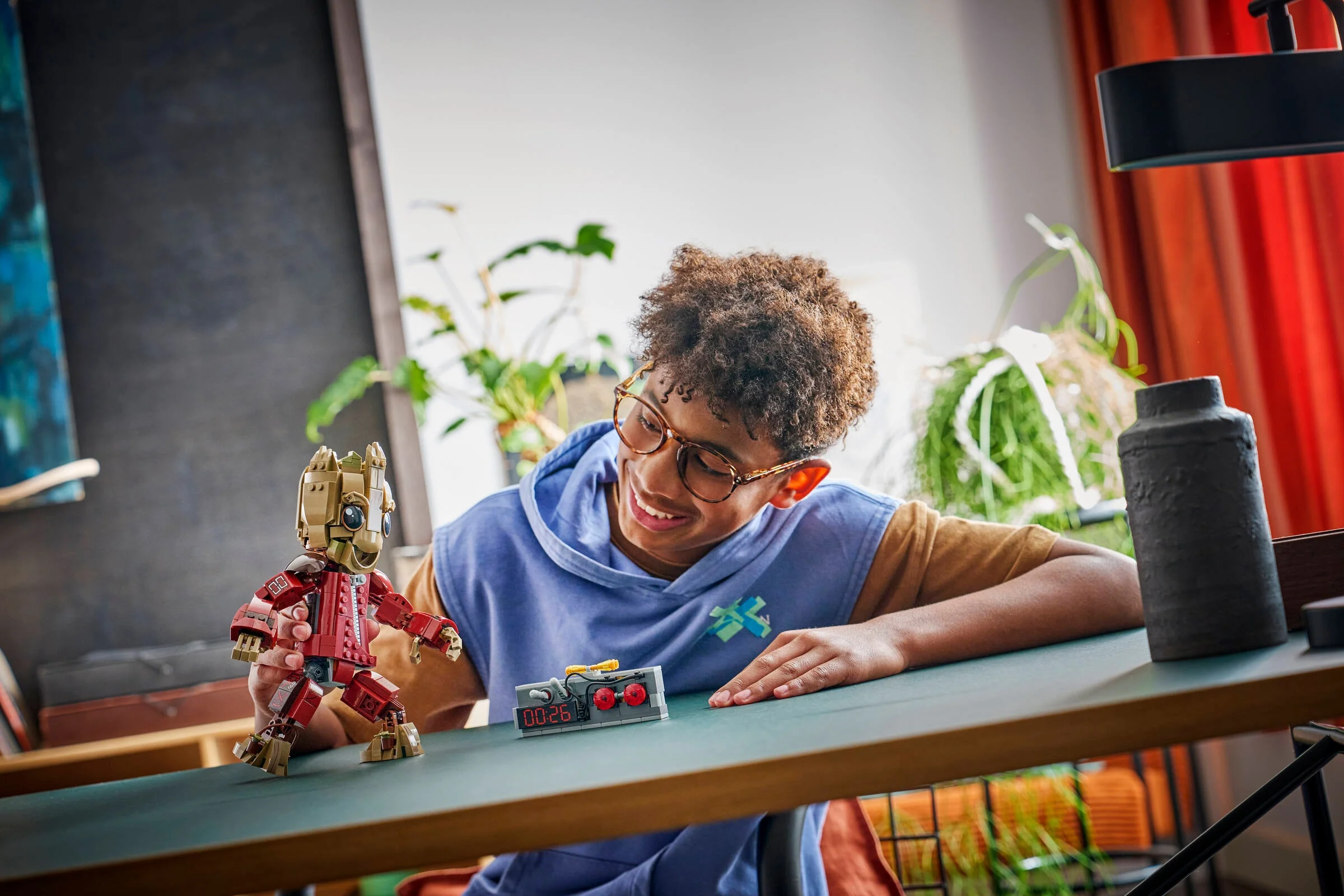 Băiat zâmbitor se joacă cu Groot Ravager și bomba construită din LEGO.