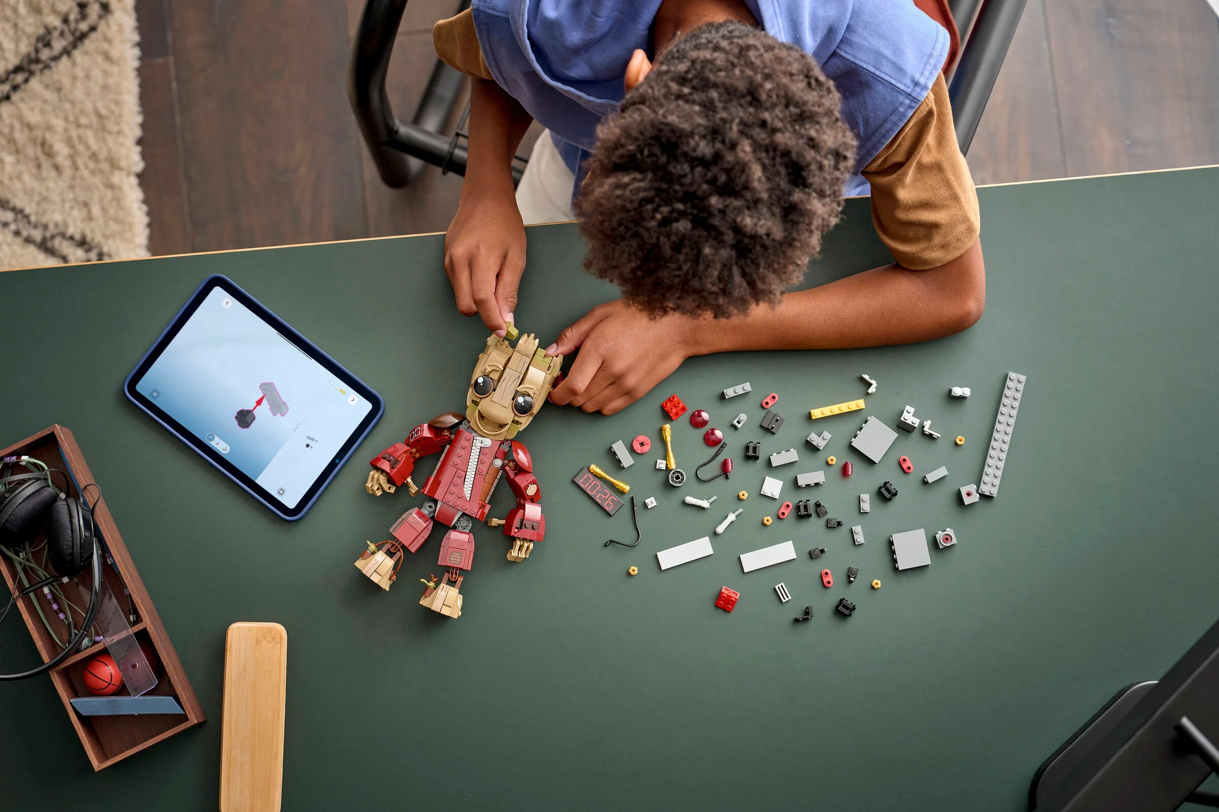 Copil construind modelul LEGO Ravager Jumpsuit Groot, urmând instrucțiunile de pe tabletă.