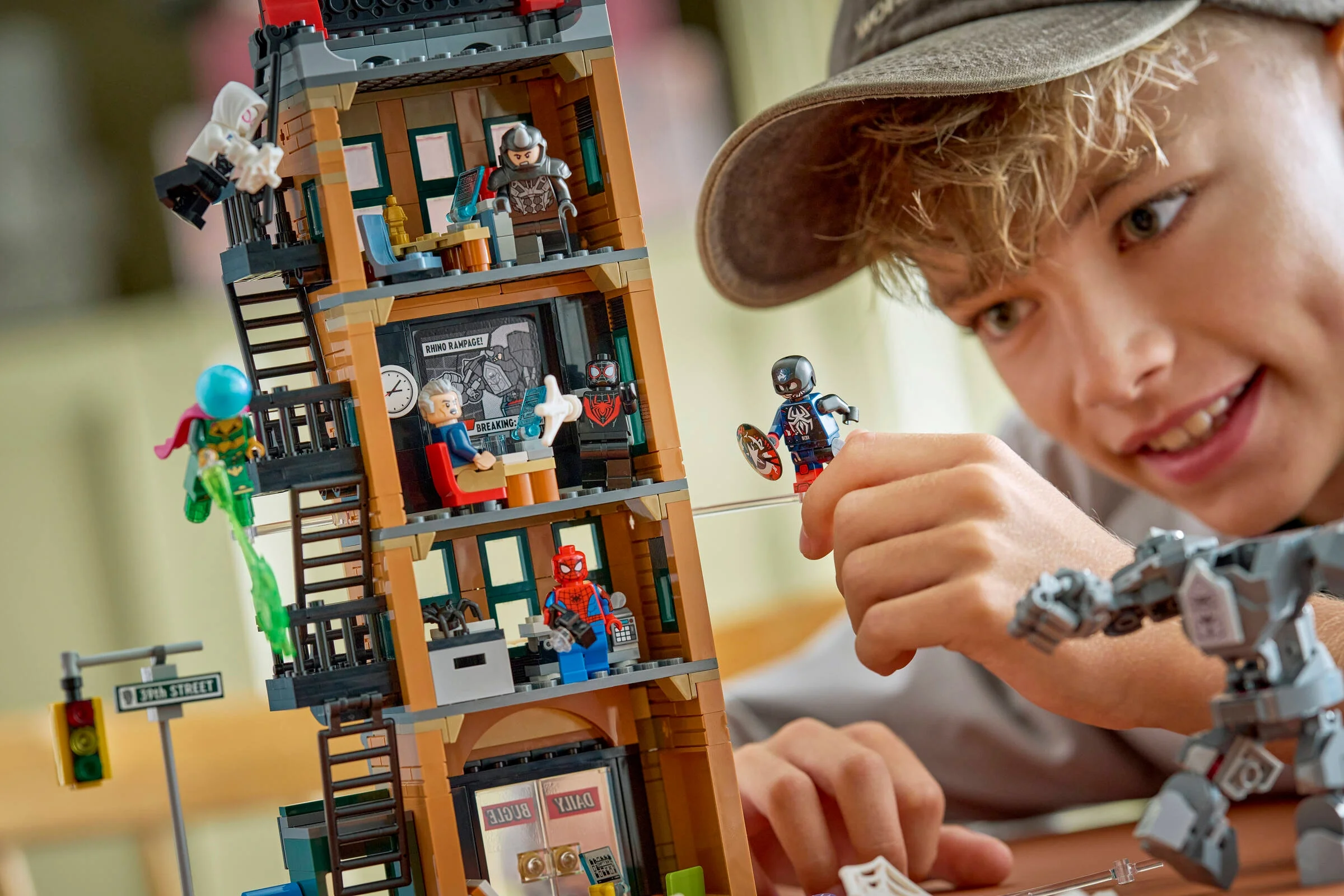 Băiat zâmbind și jucându-se cu setul LEGO Daily Bugle. Distracție cu supereroi!