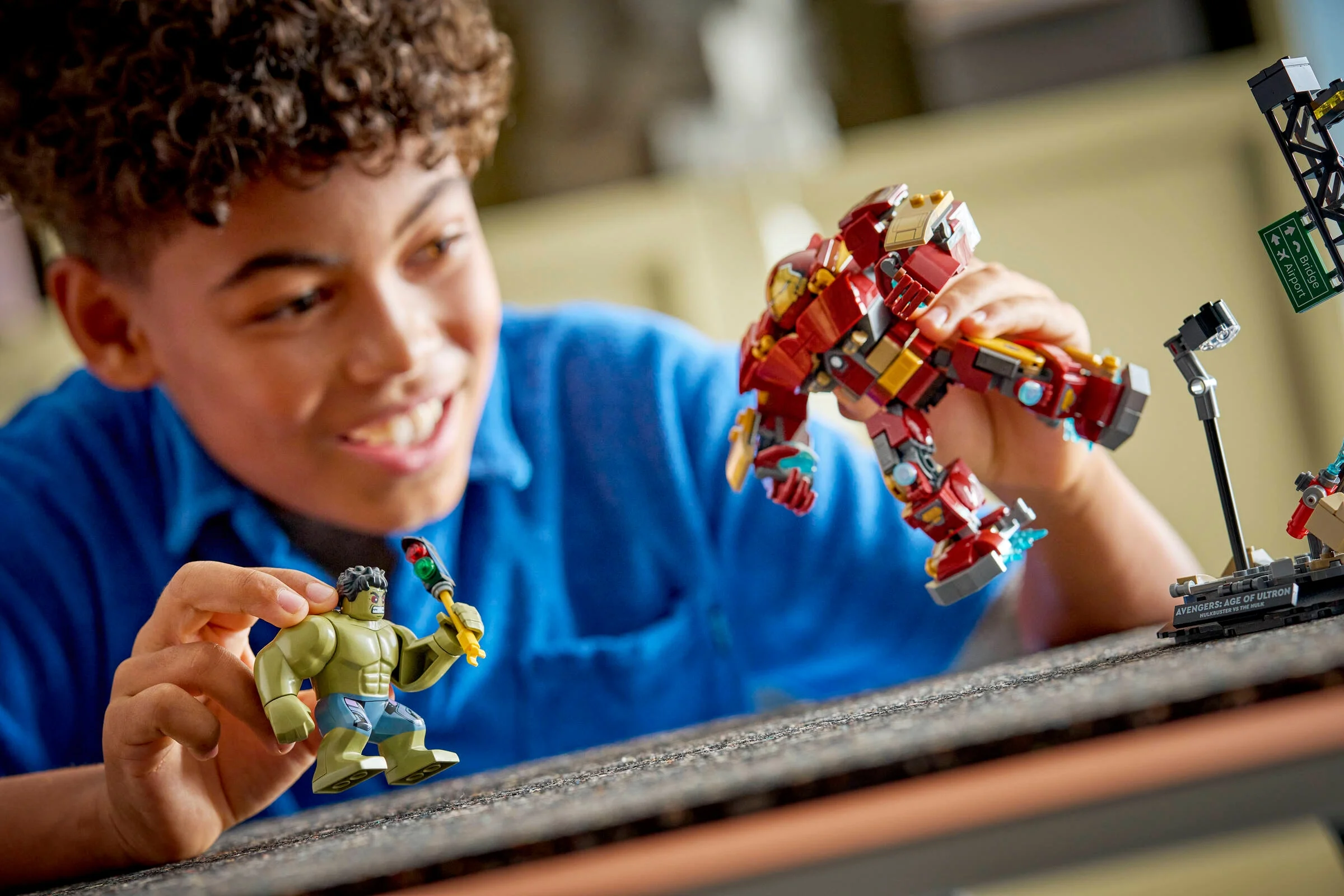 Băiat zâmbitor se joacă cu setul LEGO Hulkbuster vs. Hulk. Bătălie epică!