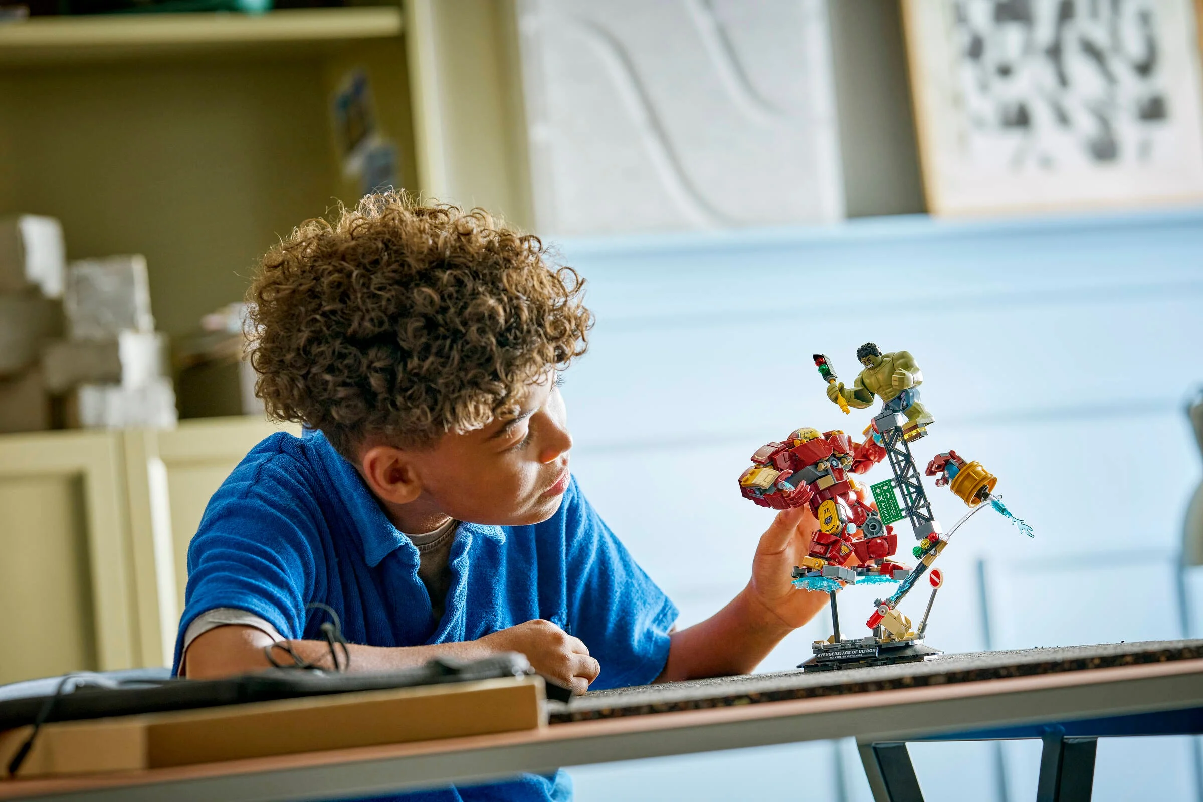 Copil admirând setul LEGO Hulkbuster vs. Hulk. Scene din Age of Ultron, detaliată și interactivă.