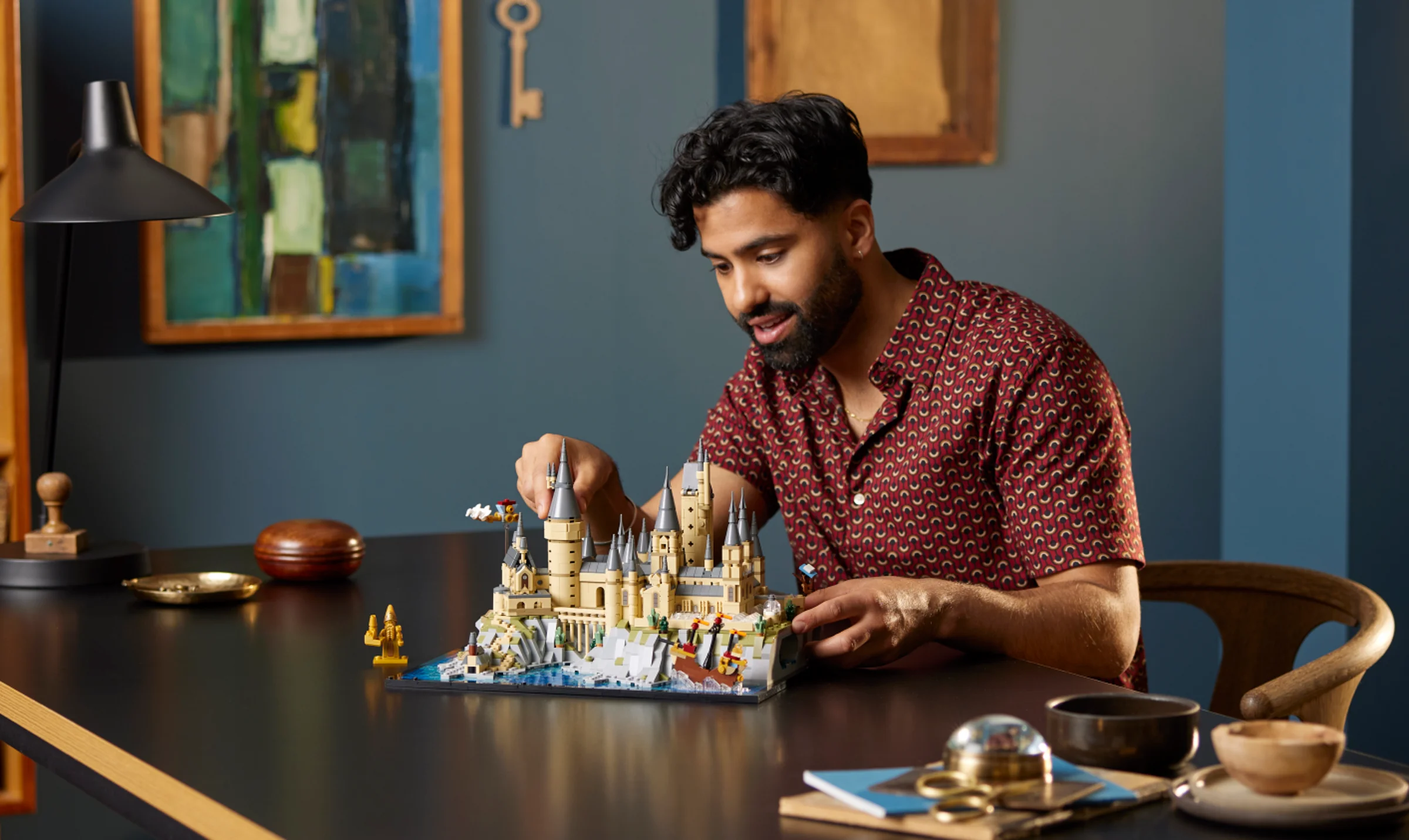 Bărbat construind castelul Hogwarts LEGO. O experiență relaxantă și detaliată. Model expus pe masă.