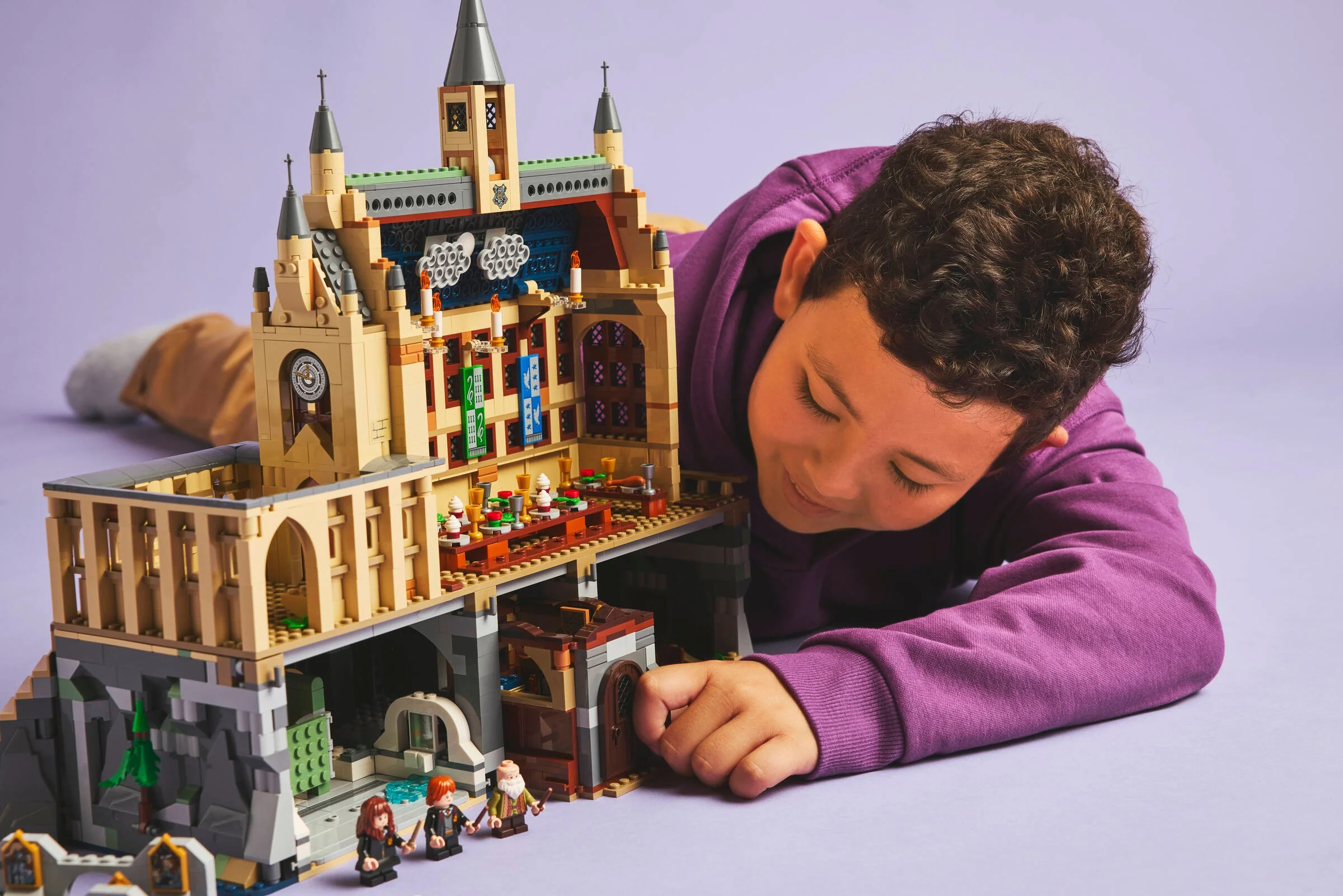 Un copil se uită atent la Castelul Hogwarts LEGO, explorând detaliile construcției.