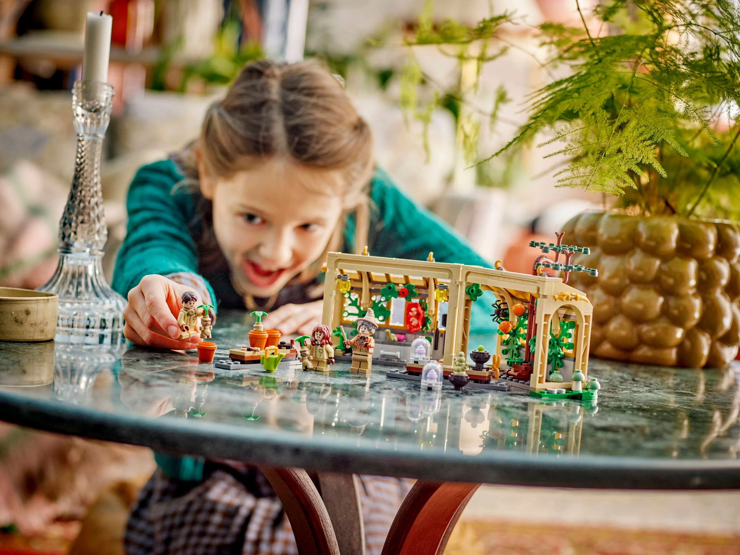 O fată se joacă cu setul LEGO Hogwarts: Clasa de ierburi, aranjând minifigurinele.