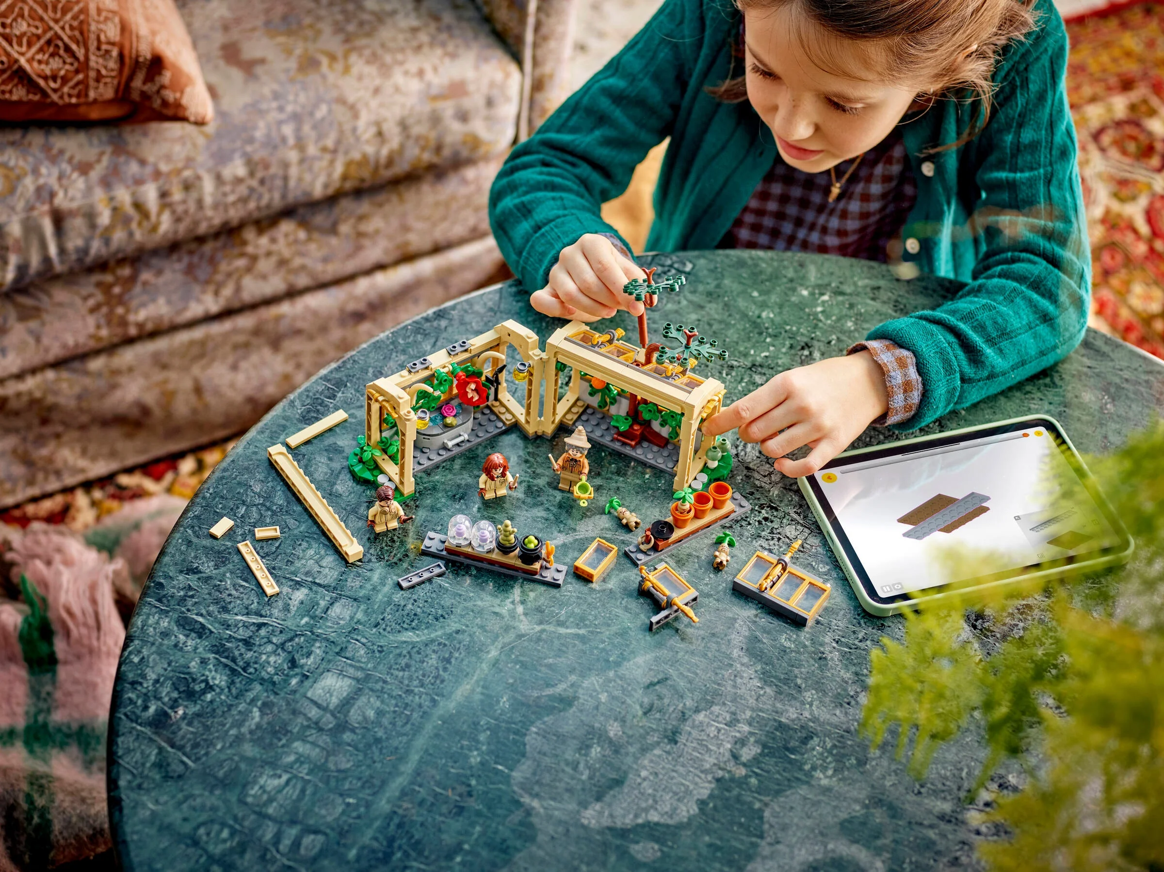 Fetiță construind setul LEGO Hogwarts Herbology Class. Scenă detaliată cu minifigurine și accesorii.