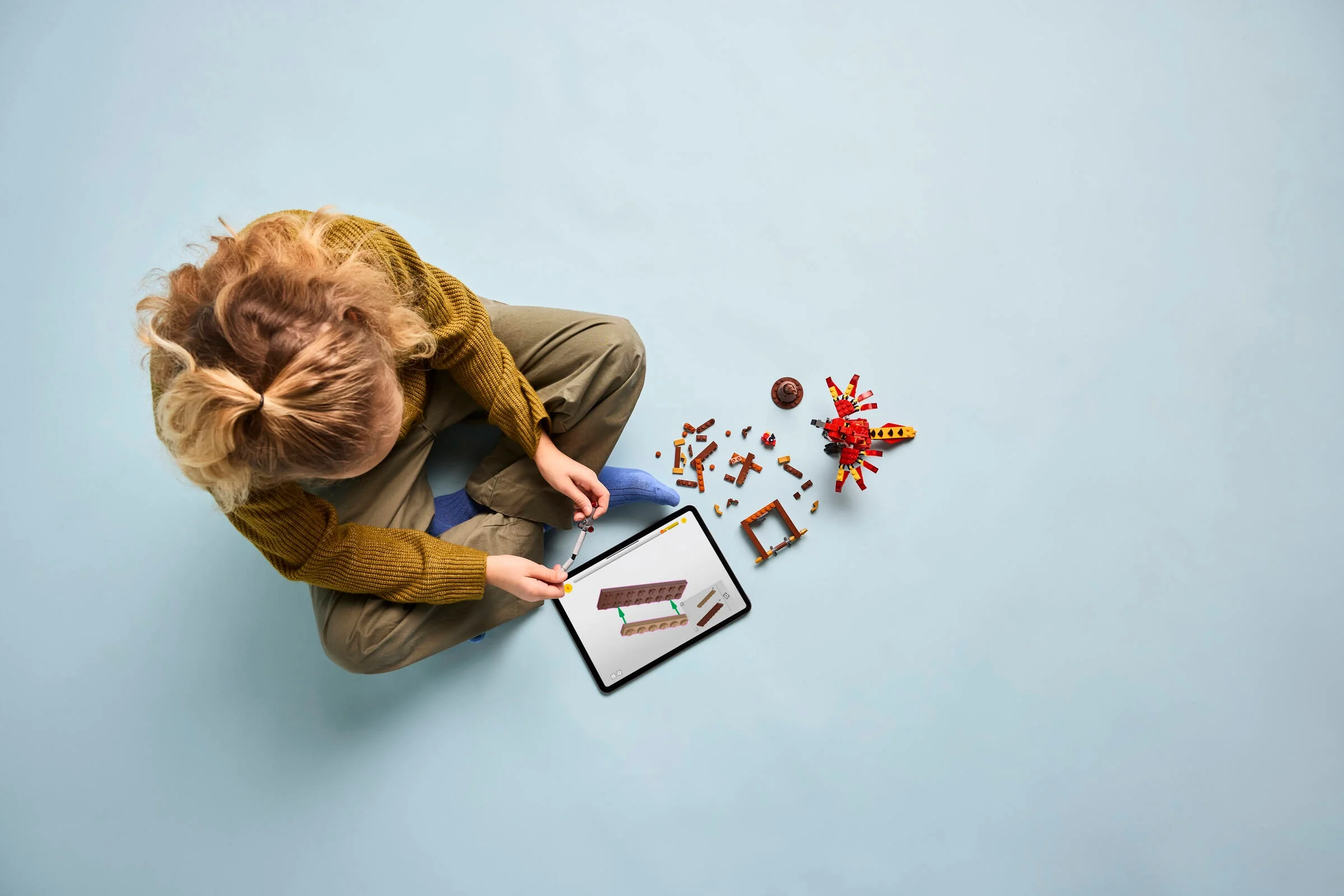 Copil construind Fawkes cu instrucțiuni digitale pe tabletă. Set LEGO Harry Potter.