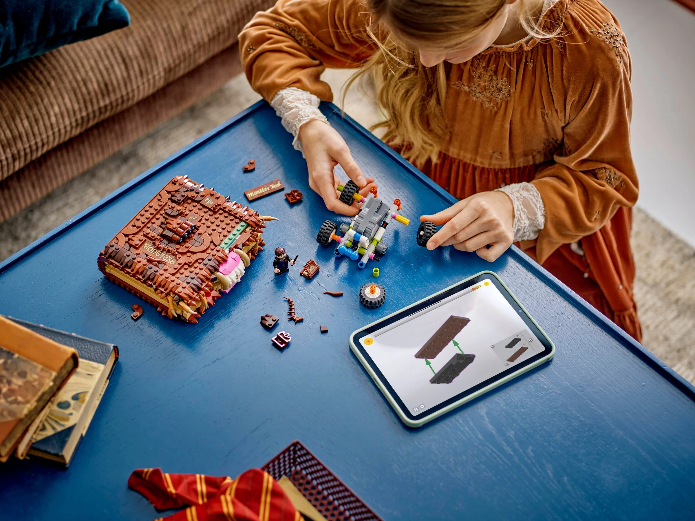 Fetiță asamblând cartea monstru LEGO, urmând instrucțiuni pe tabletă. Detaliu constructiv.